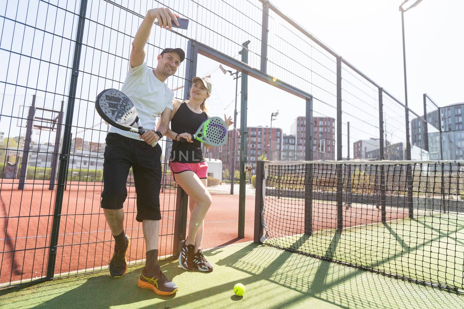 Ukraine Kyiv, April 02 2024. Young woman and man talking to each other after playing padel, walking along the net together by Andelov13