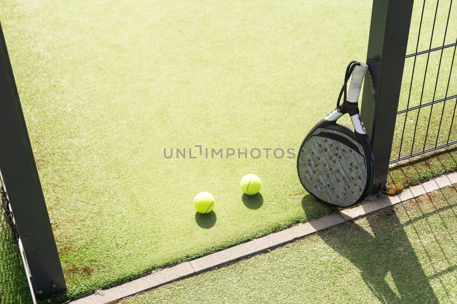 Padel racket and padel ball on a green court in the sunset. High quality photo