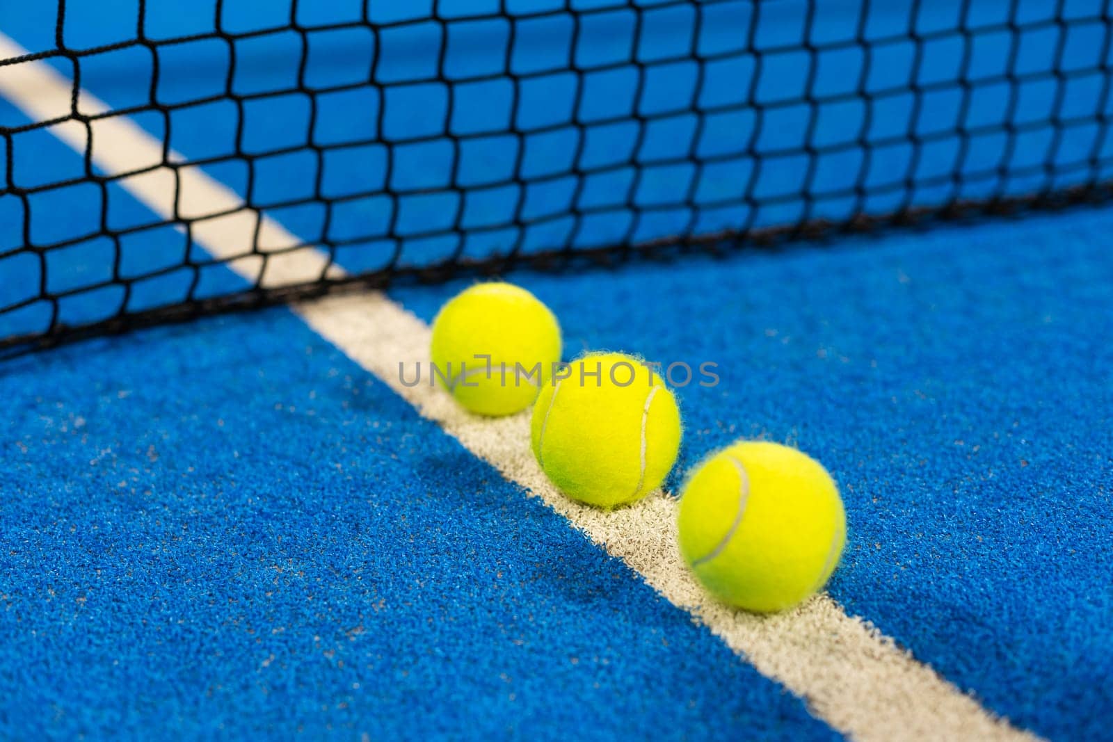balls near the net of a blue padel tennis court by Andelov13