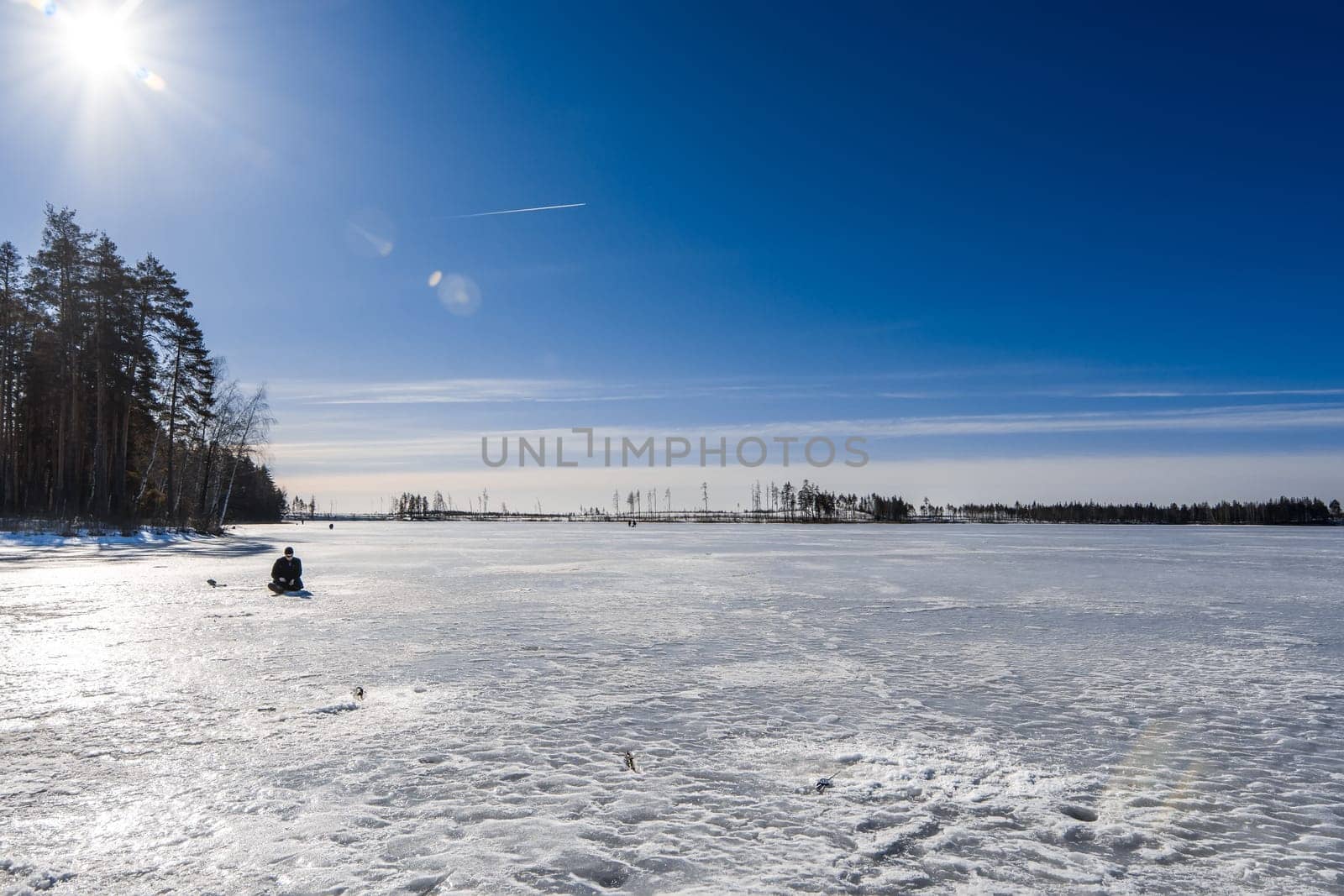 lonely fisherman is fishing in the winter on a Sunny day
