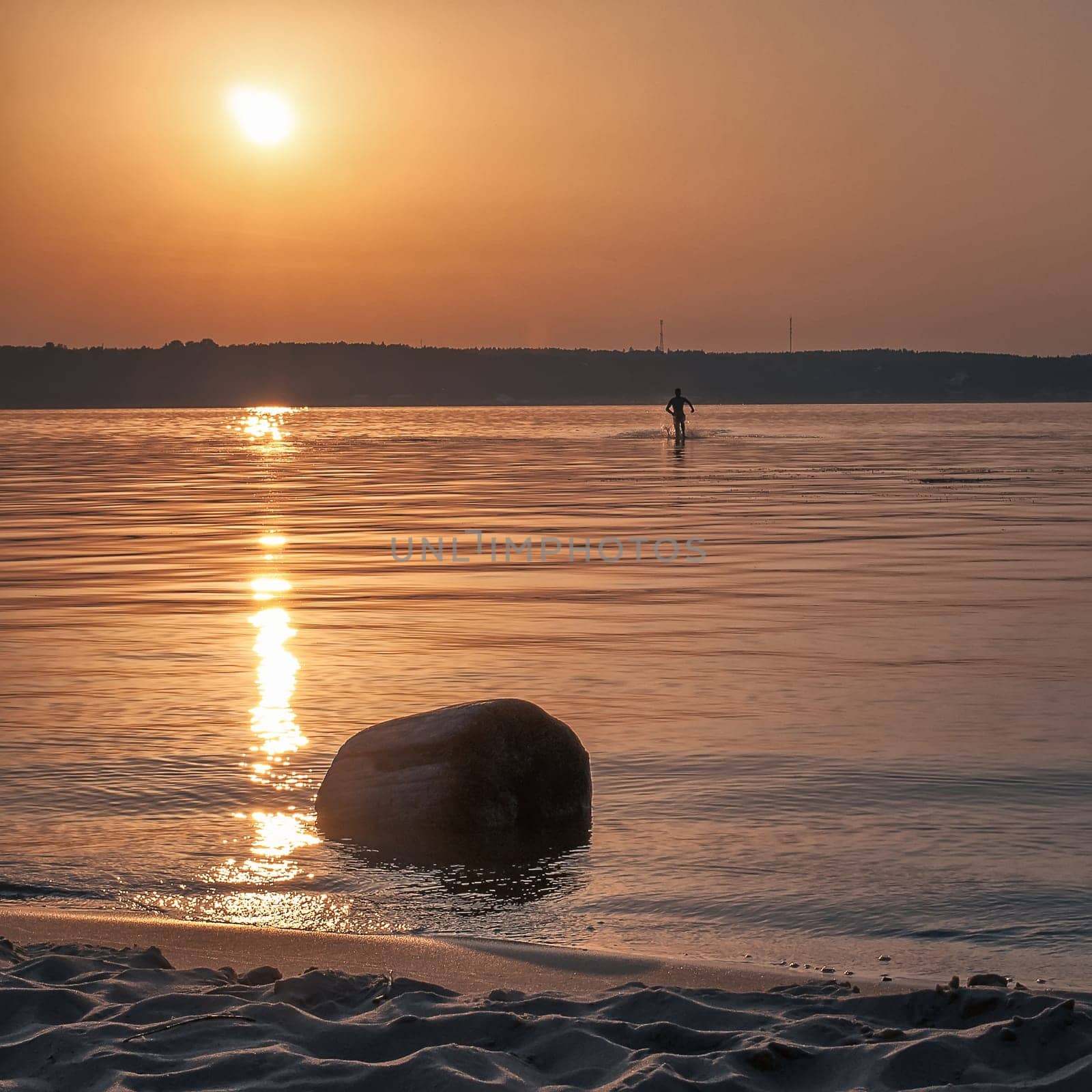 silhouette of a man running on water at sunset in the summer under the sun