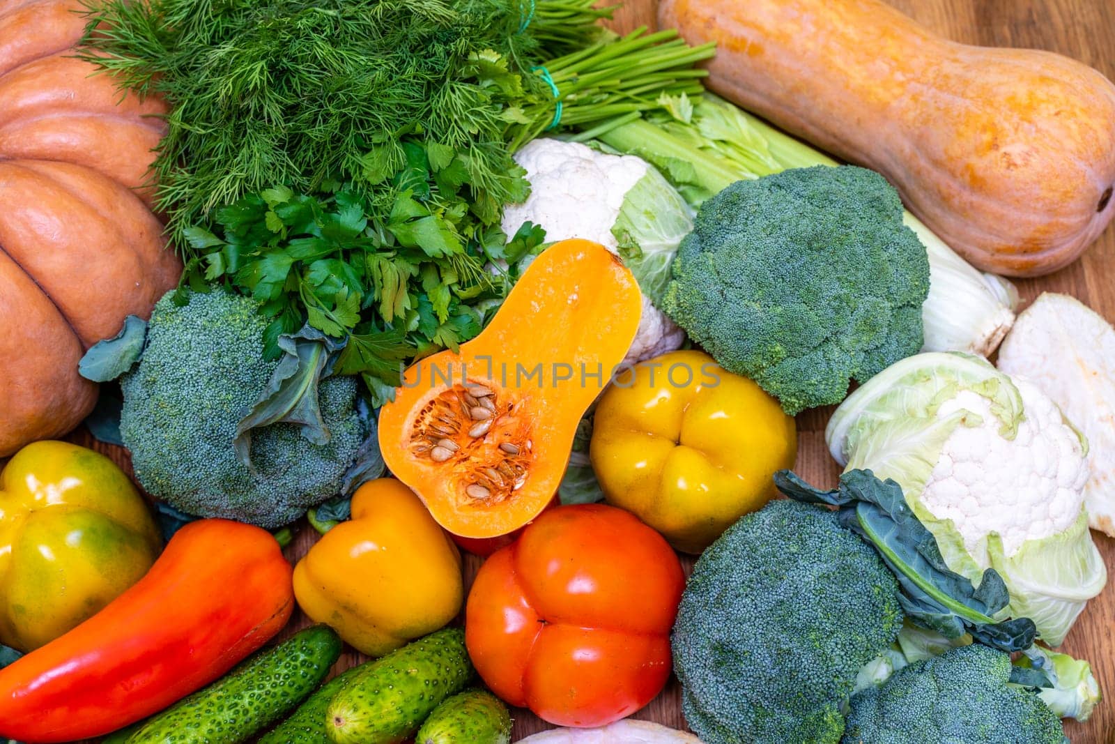 Various vegetables are laid out on a wooden table. Large assortment of vegetables food. pumpkin cabbage broccoli pepper tomatoes carrots and others by Matiunina