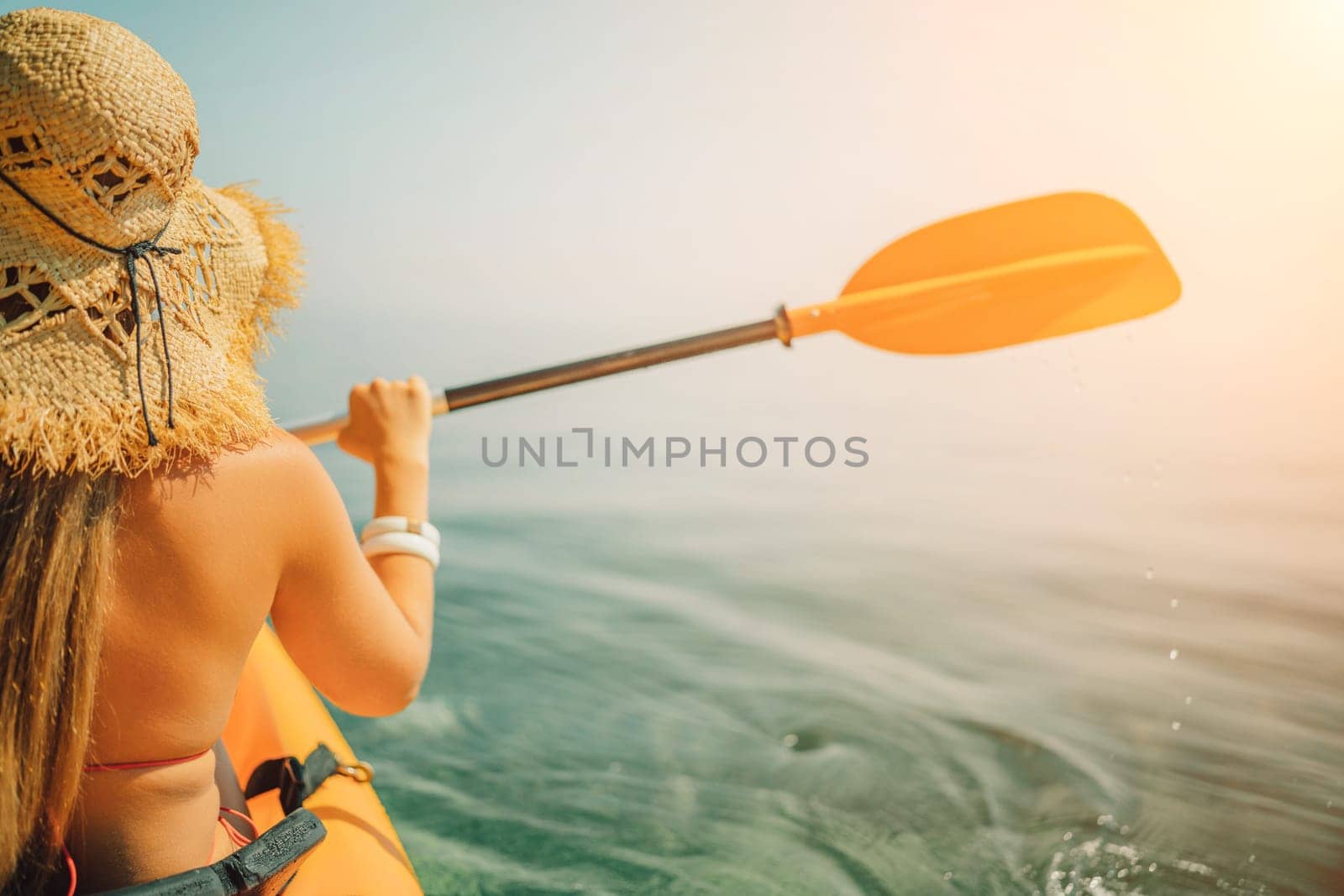 woman straw hat paddling a kayak on a lake. The sun is shining brightly, creating a warm and inviting atmosphere. by Matiunina
