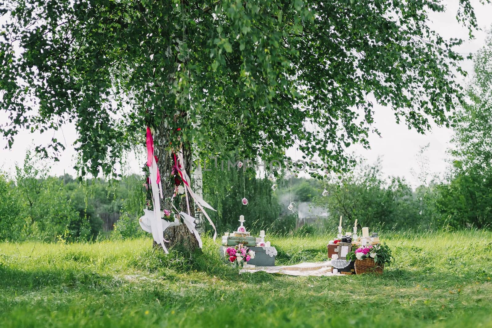 wedding decor from the flowers and decorations with a swing under the trees outdoors in summer