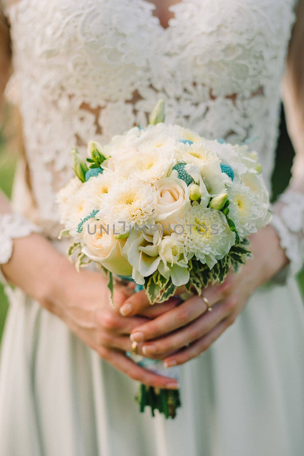 wedding bouquet of white roses in hands of bride in wedding dress