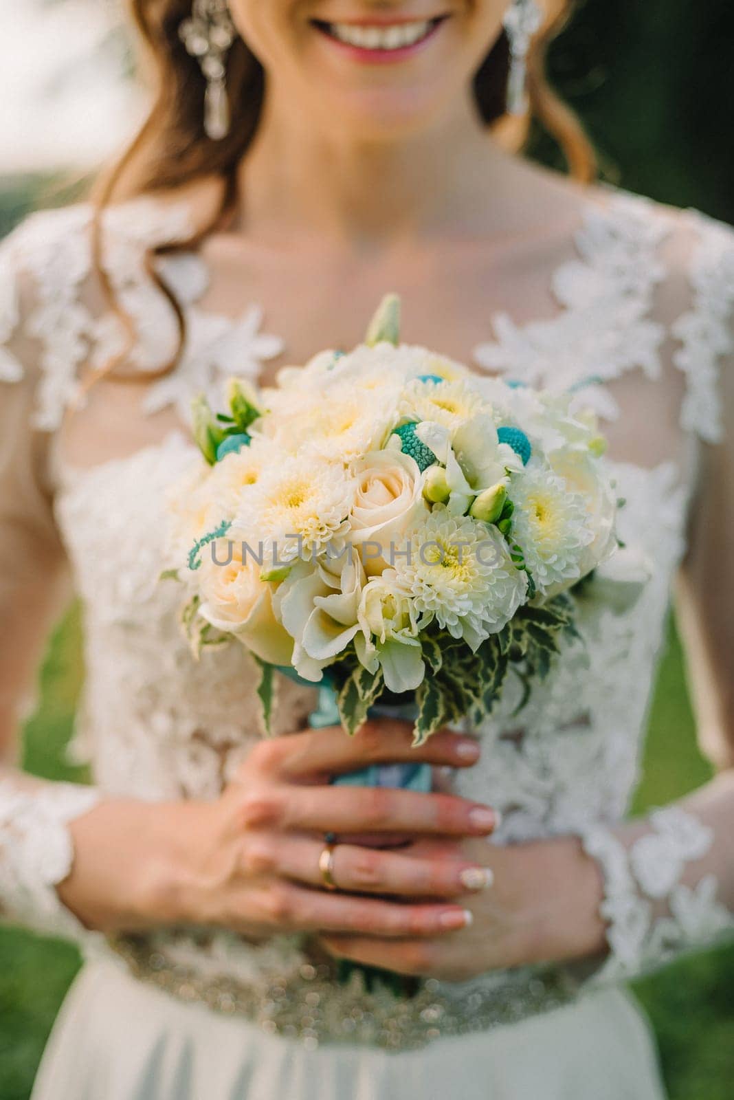 wedding white bouquet of roses in the hands of a happy bride in elegant white wedding dress