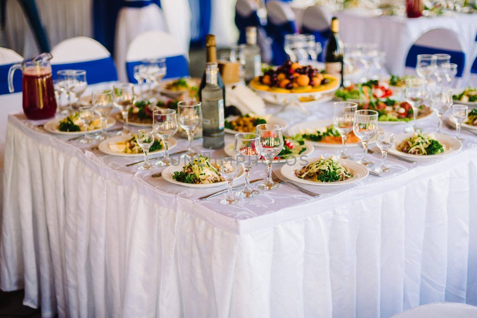 festive table with a white tablecloth with food and empty glasses in restaurant prepared for wedding
