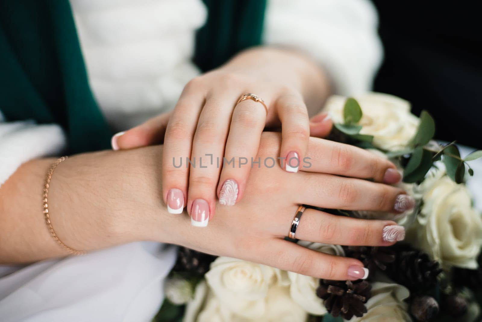 French manicure closeup on hands of the bride with rings