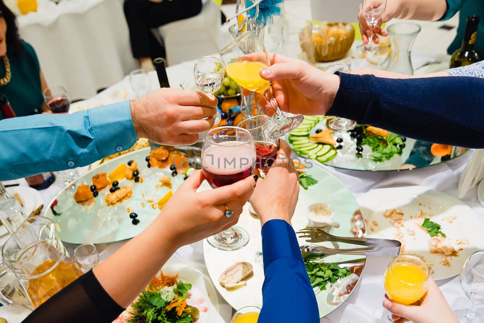 many hands with different glasses of wine clink and jingle in the holiday