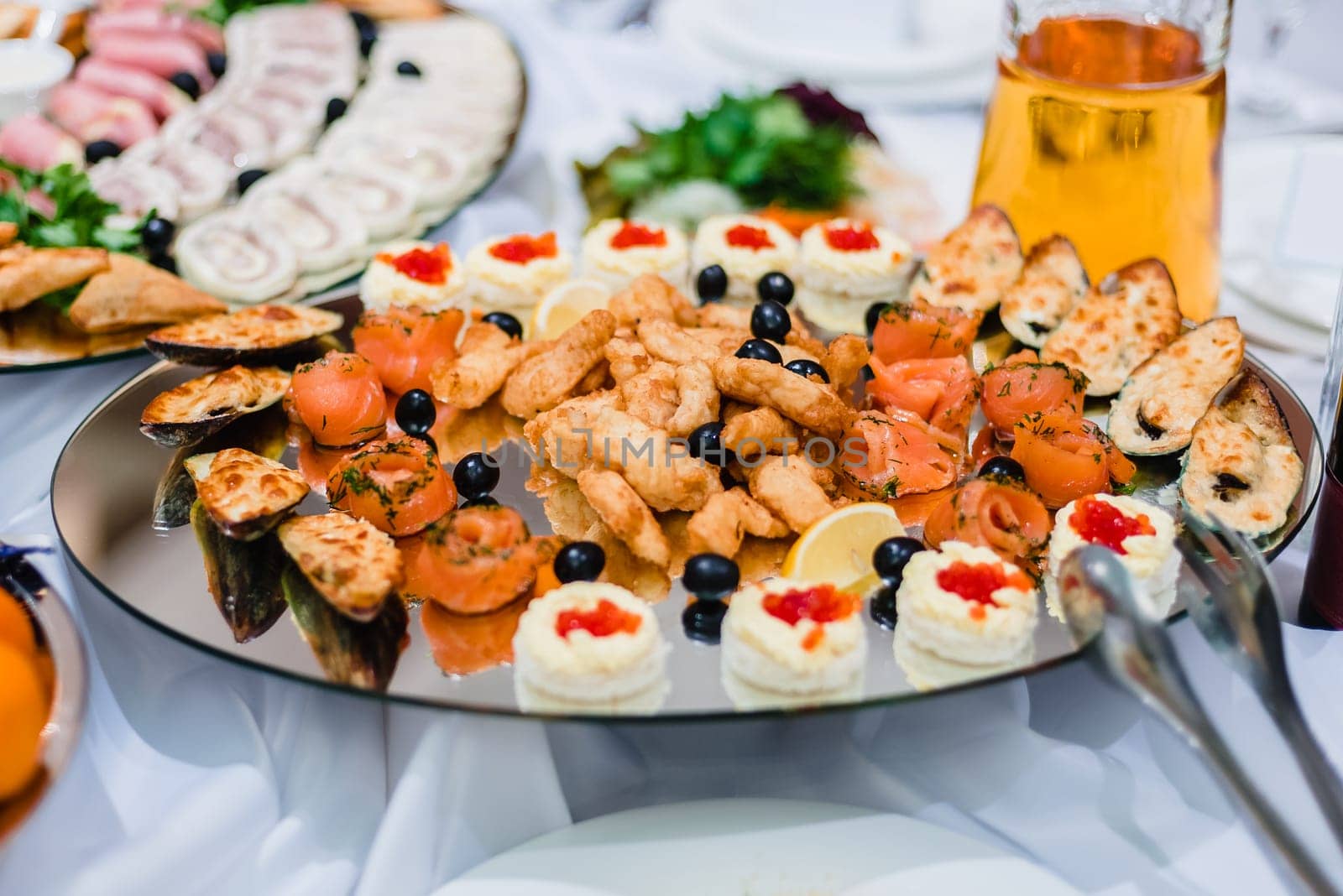 fish dishes of salmon, mussels and caviar with olives on a plate in the restaurant