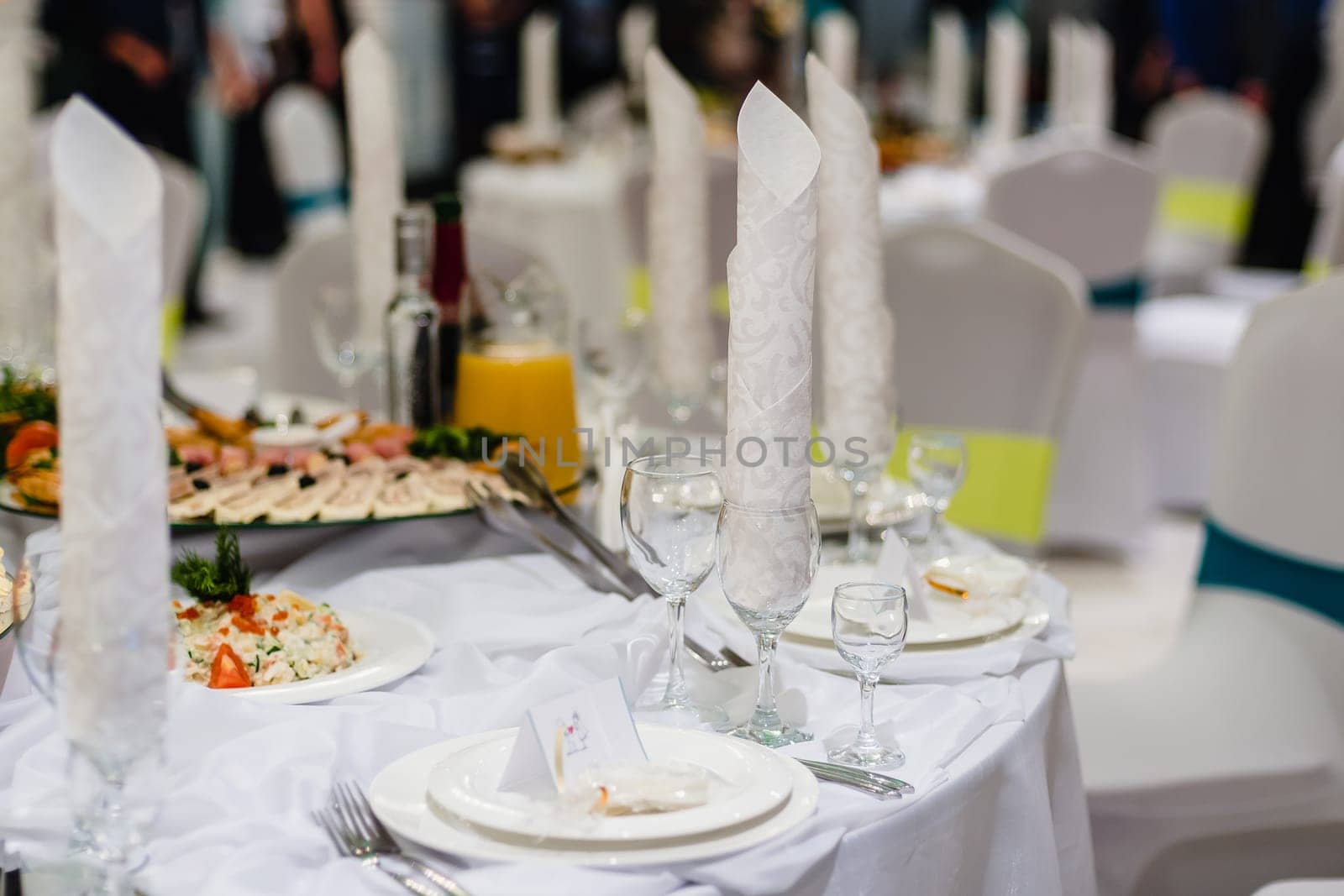 white festive laid table in the restaurant with glasses and plates prepared for dinner