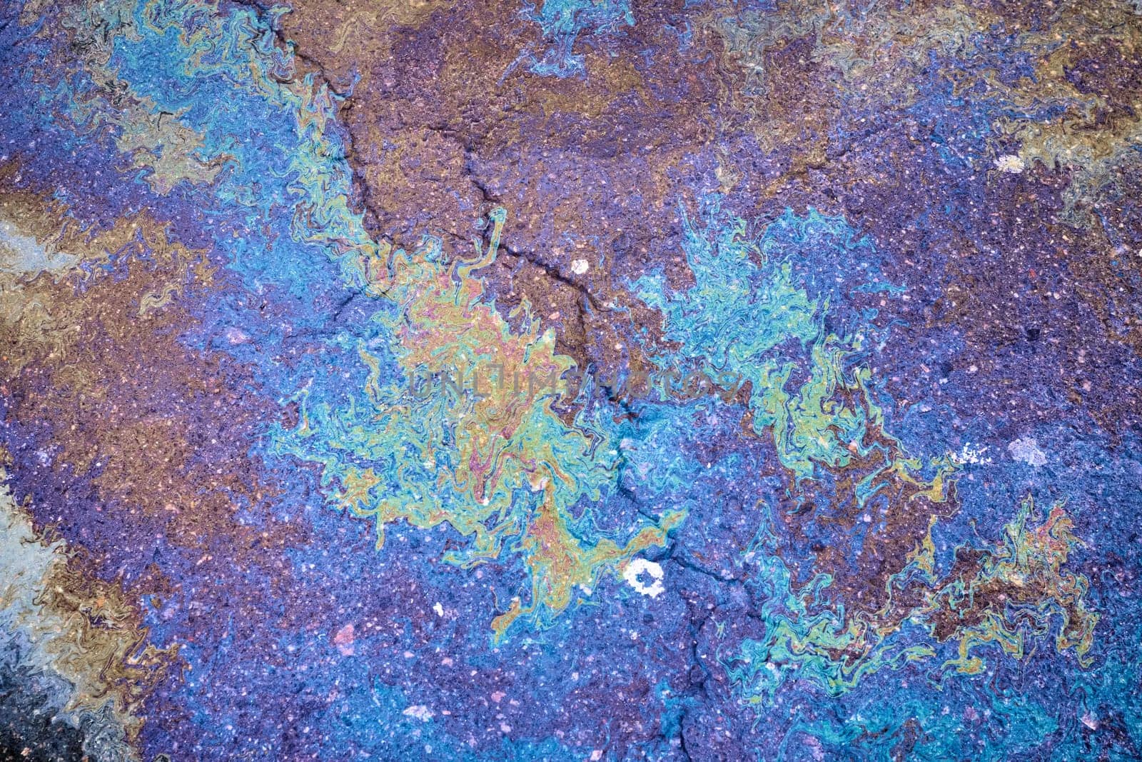 Texture of colorful petrol oil spill on wet pavement Slick industry oil fuel spilling water pollution