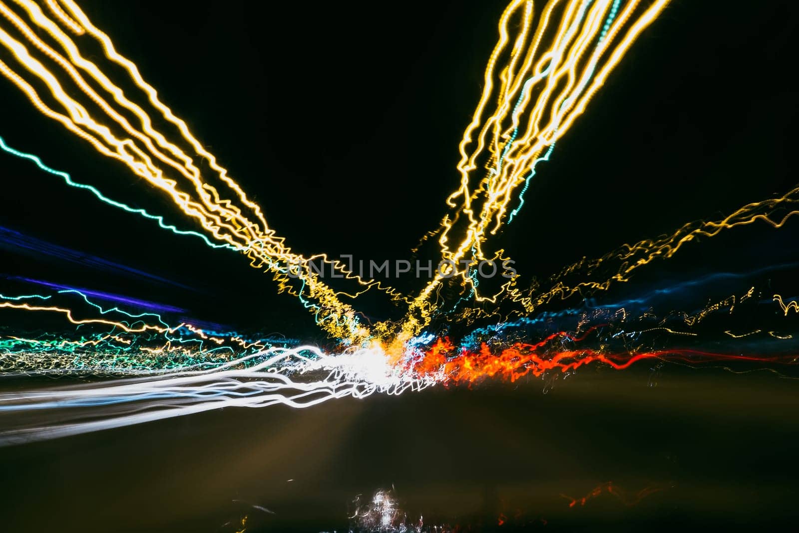 bright colored blurred traces from cars and lights on the road at night with a dark background