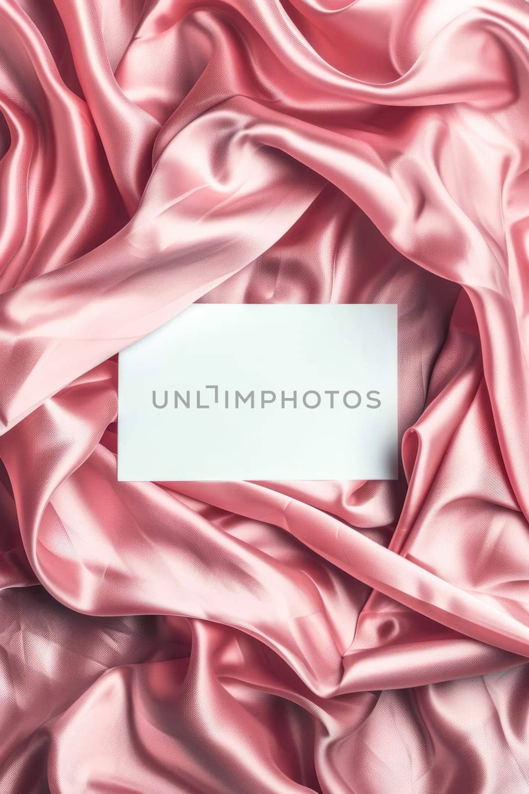 Minimalist aesthetic mockup of white blank A5 envelope on pink silk fabric.