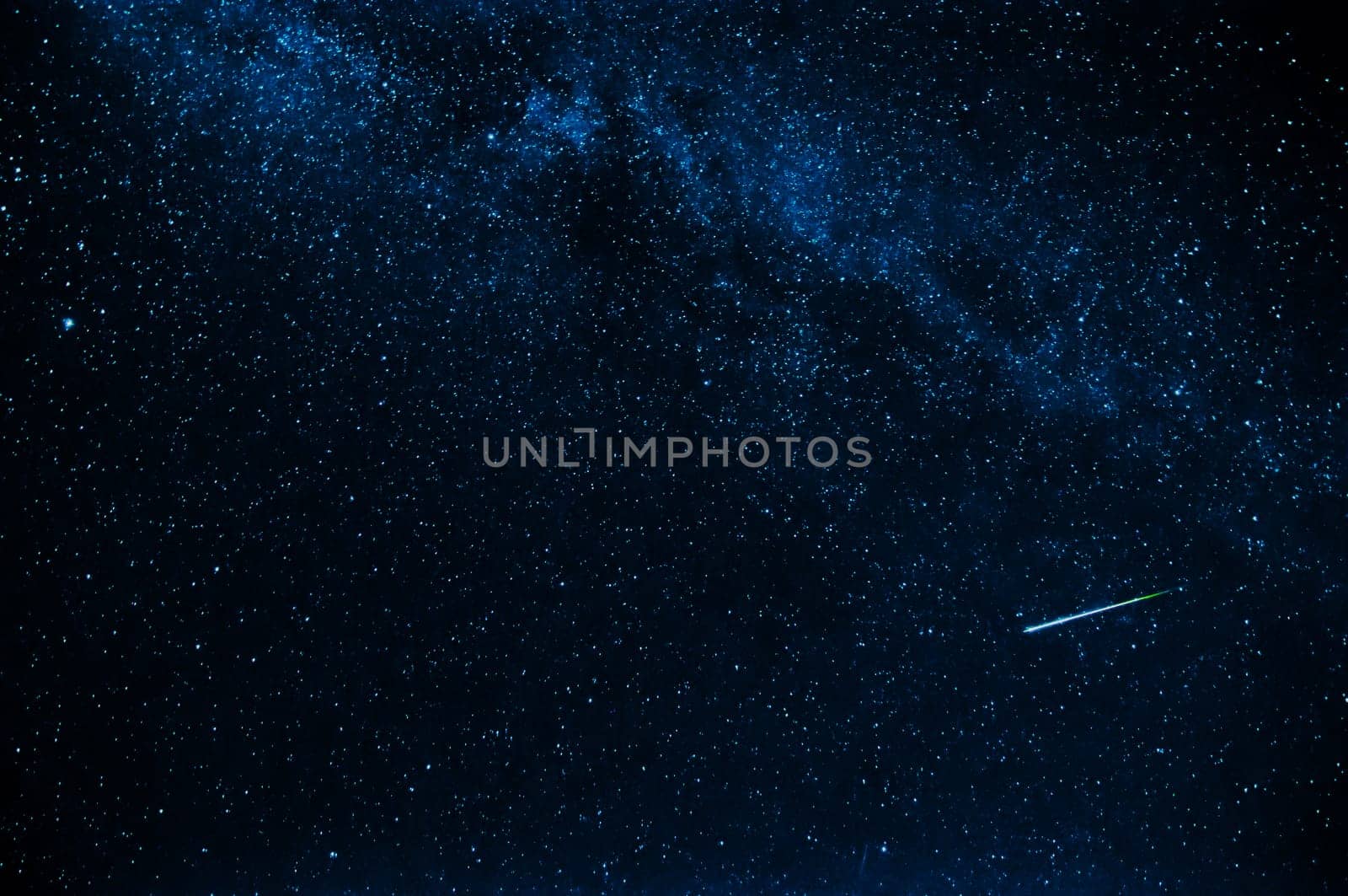 shooting star in background a starry blue dark sky at night