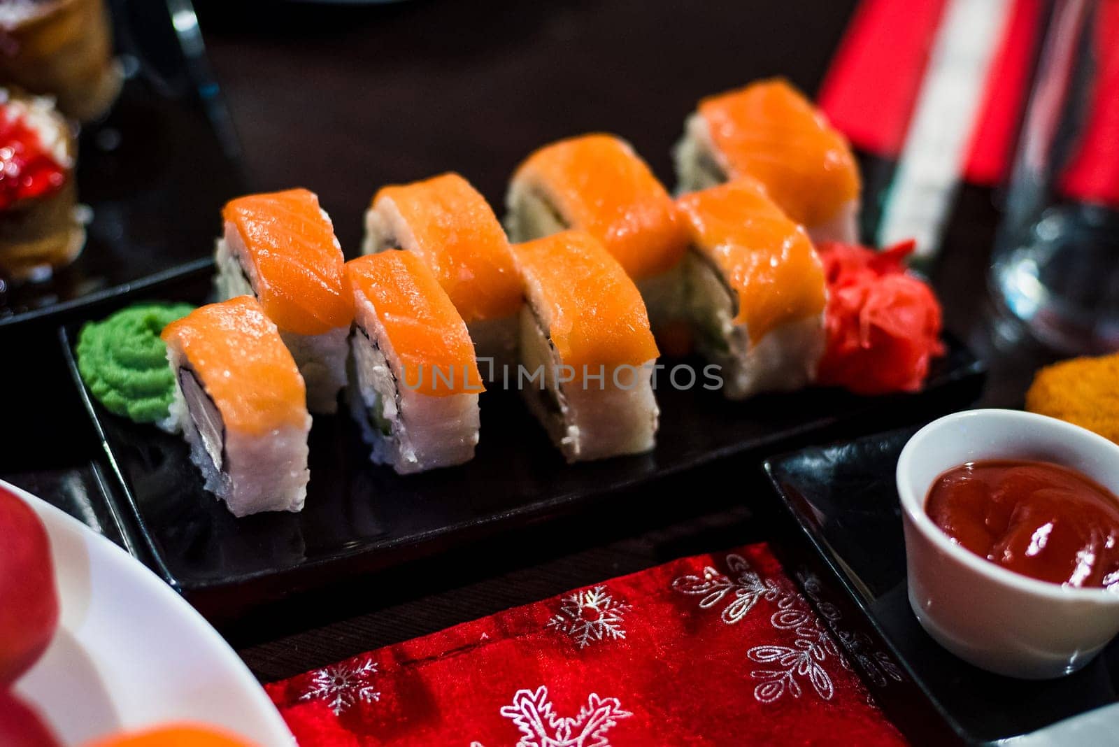 rolls with fish and avocado on a plate with sauce, ginger and wasabi