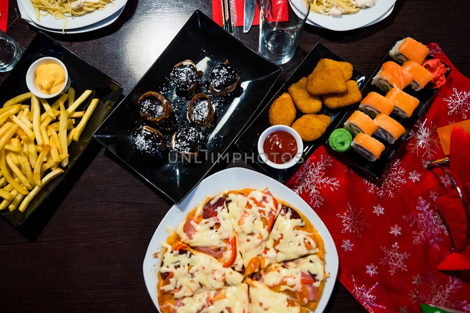 pizza, rolls, baked potatoes and an assortment of food on a dark table