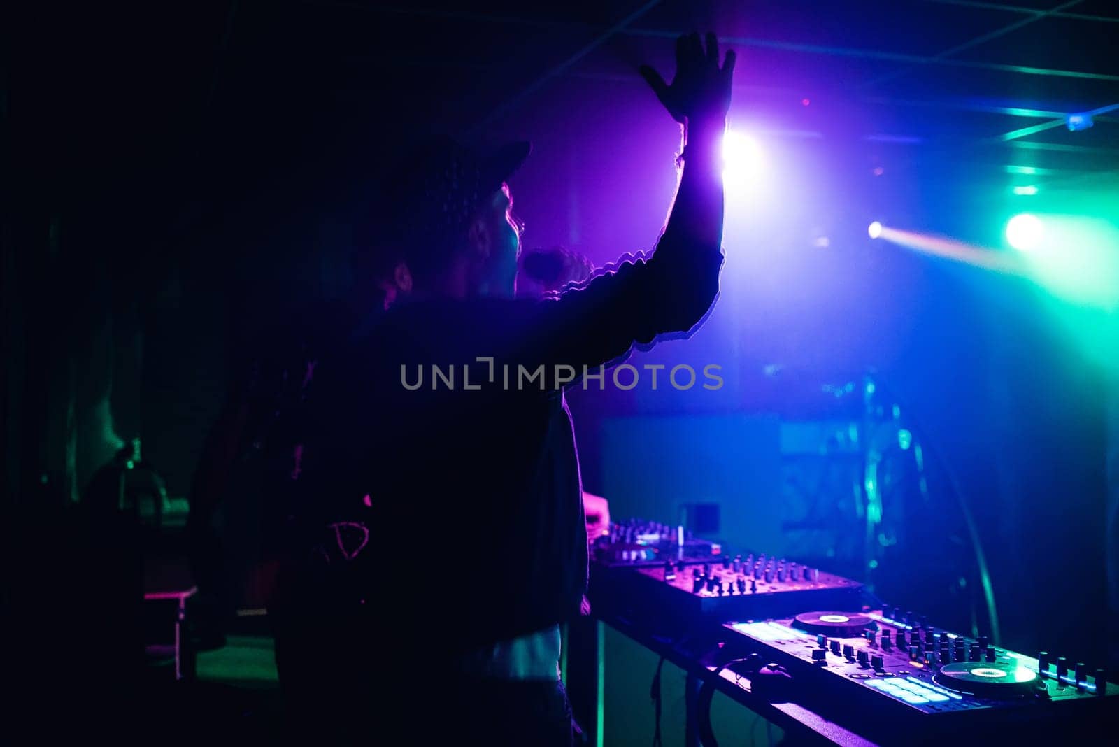 MC DJ waving his hands and shouting into the microphone in a nightclub at the party blurred and in motion