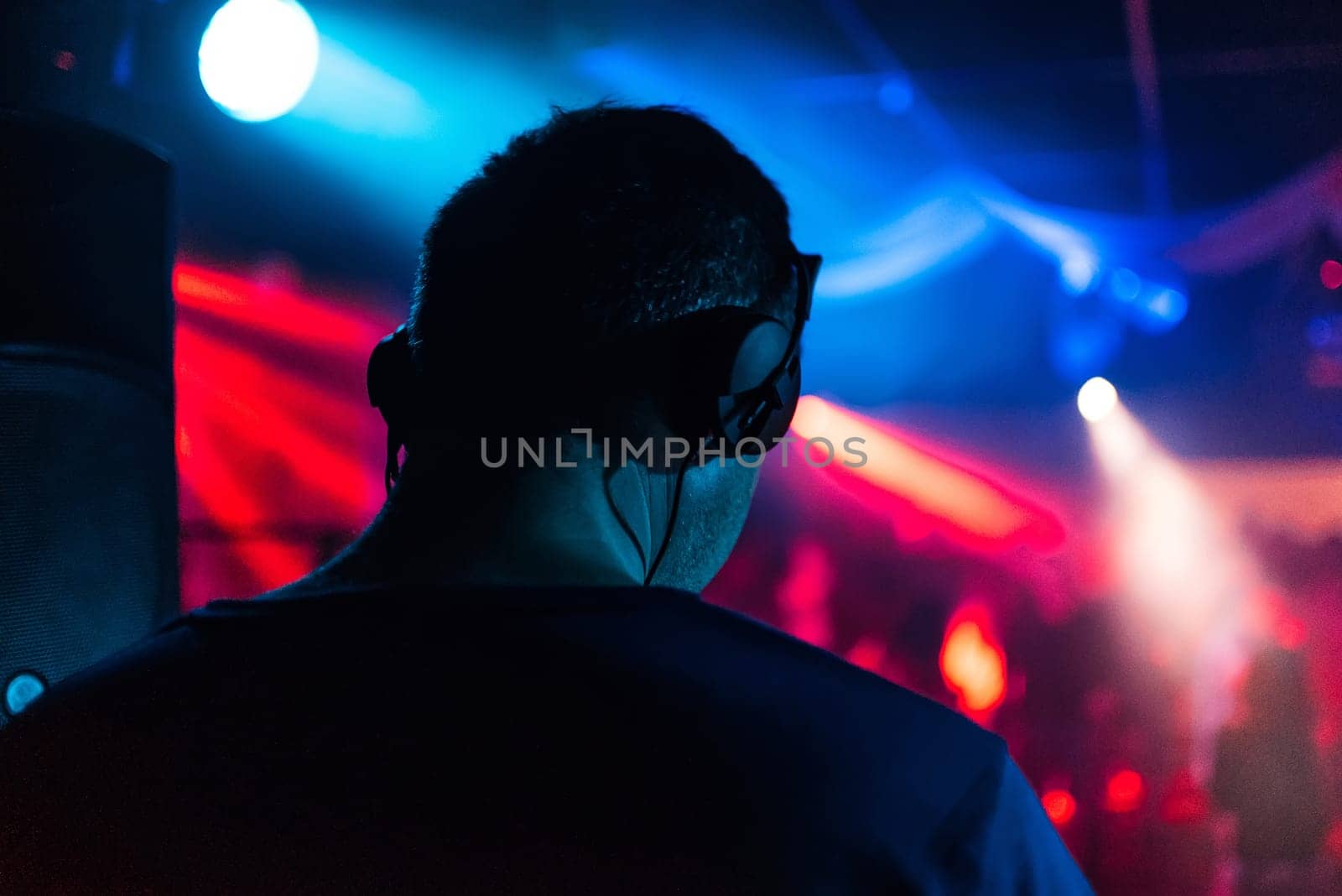 head of a DJ with headphones playing back the event in the night club music