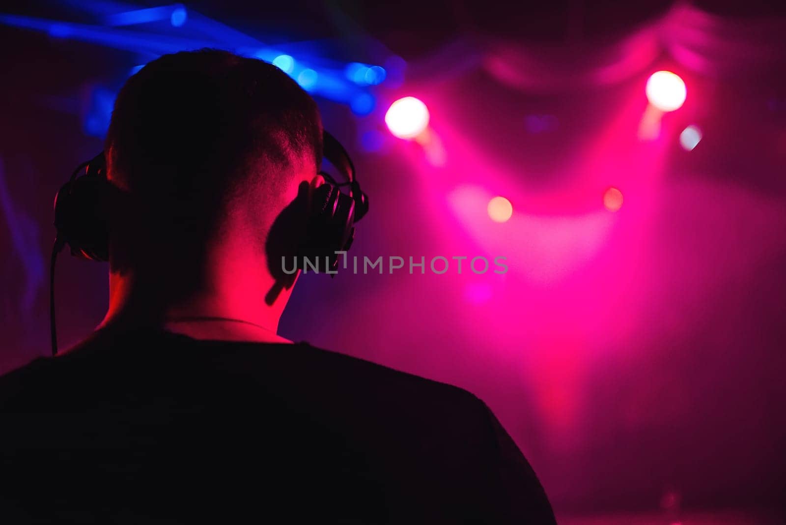 head DJ headphones from the back closeup of a musical event with bright blurred background