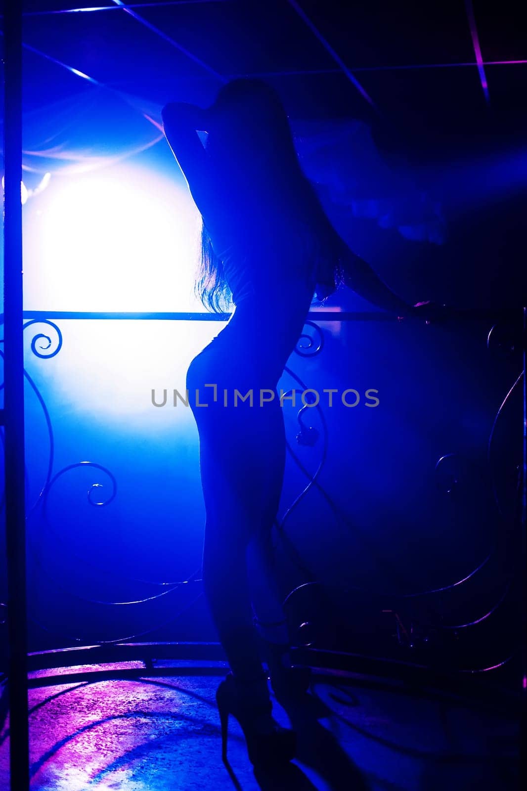 slim sexy flexible girl posing on the nightclub scene silhouette with blue light