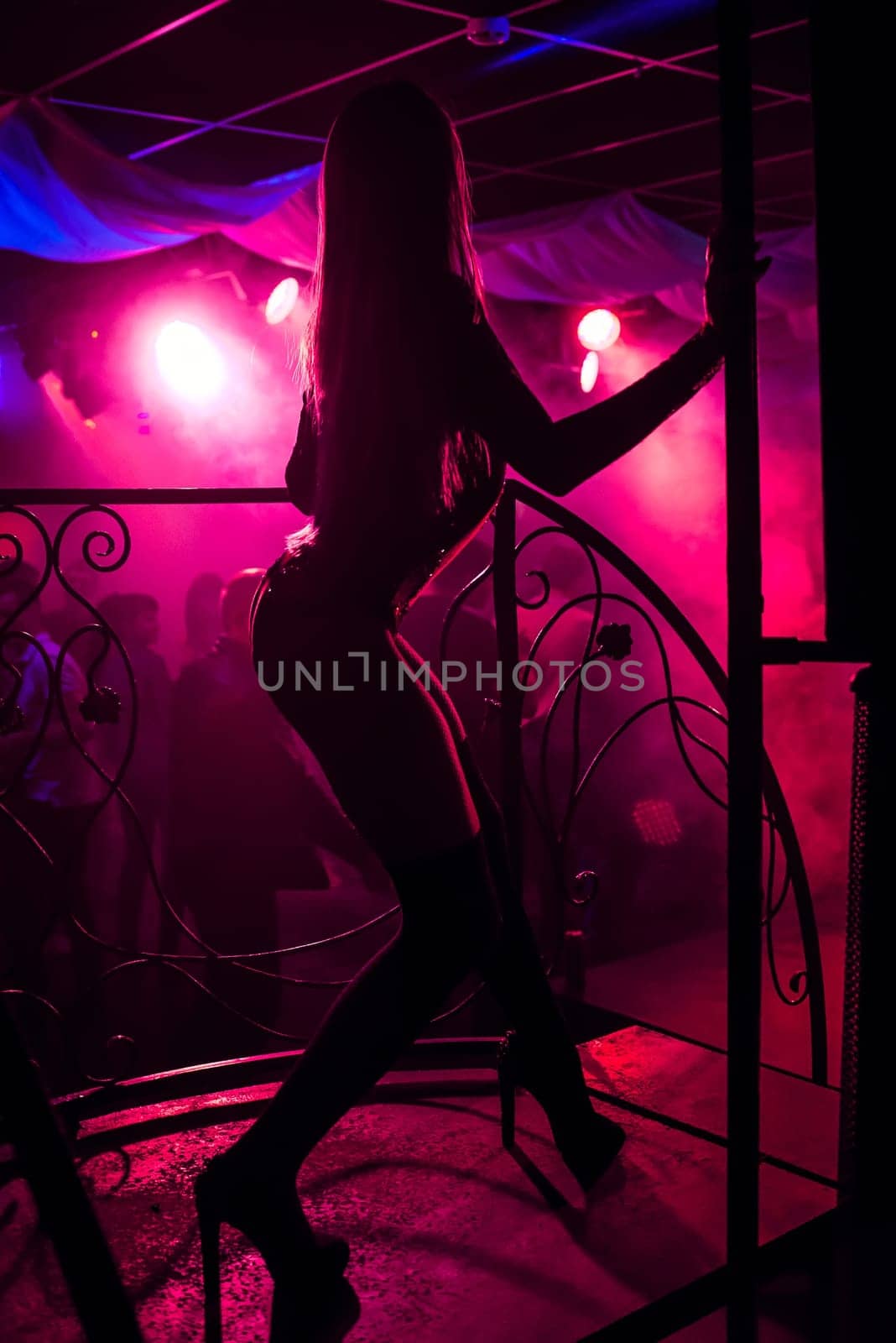 young girl go-go with a slender sexy figure posing with long legs in high heels on stage