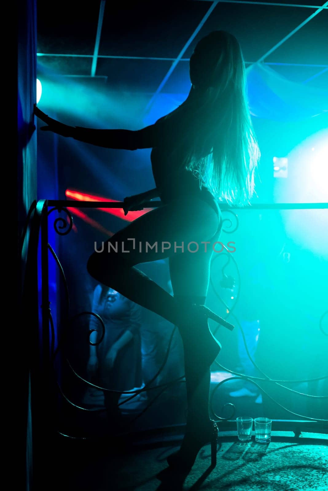 young girl with a slender body dancing on the stage dance floor night club with bright colored background
