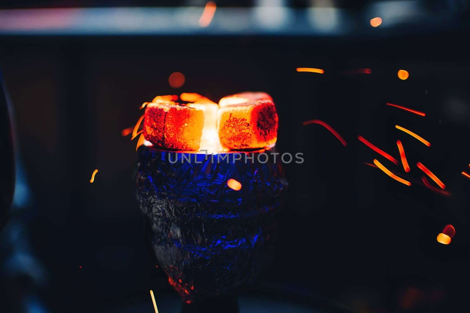 hot coal on the bowl of the hookah is heated with a flying red sparks for traditional Asian holiday and Smoking