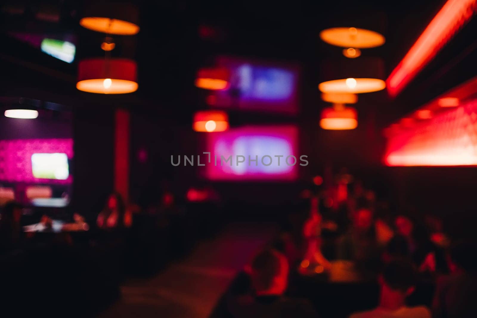 blurred dark interior of the bar with a defocused rest people and colorful bokeh