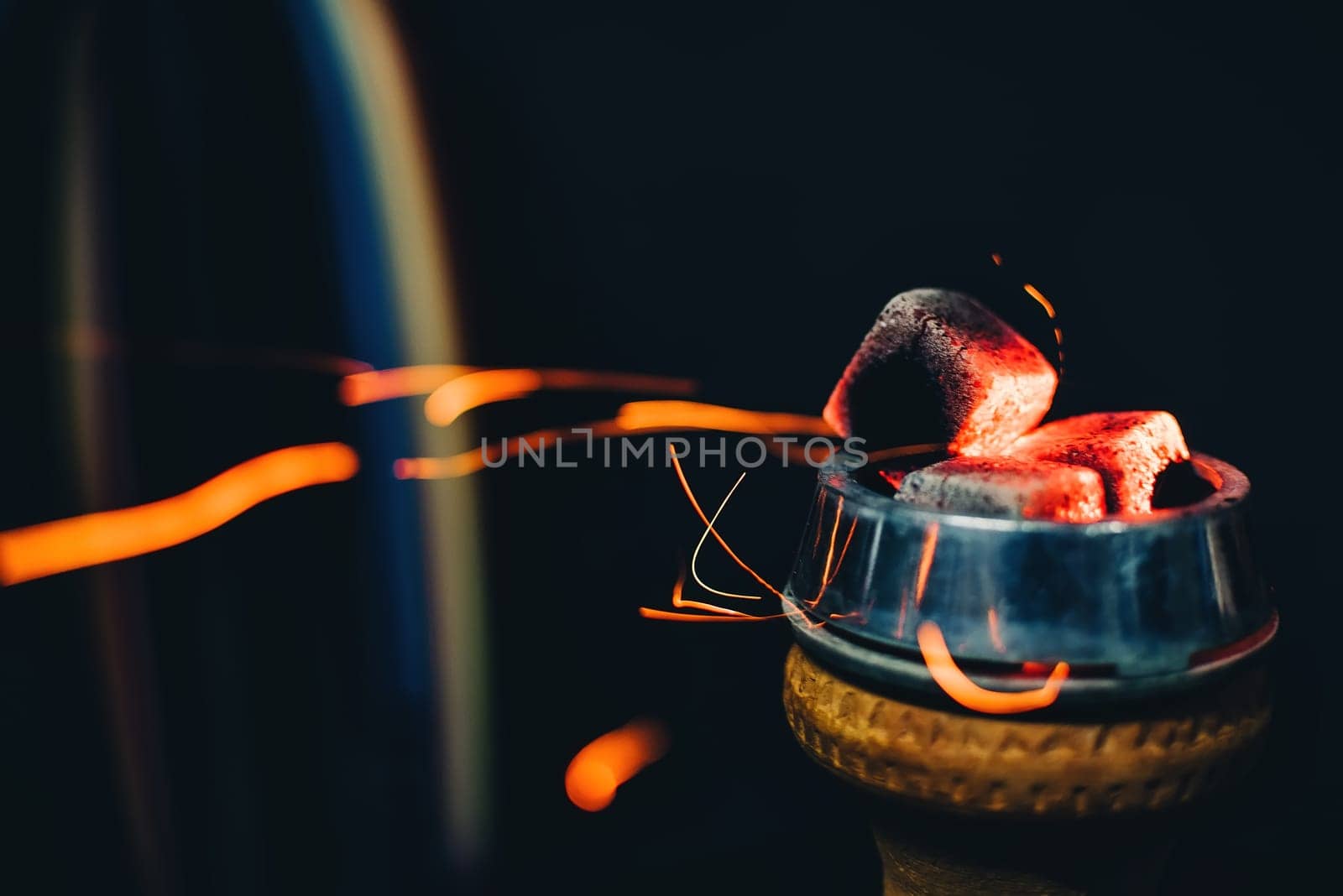 coals on the bowl of the hookah for tobacco Smoking close up with sparks on a dark background