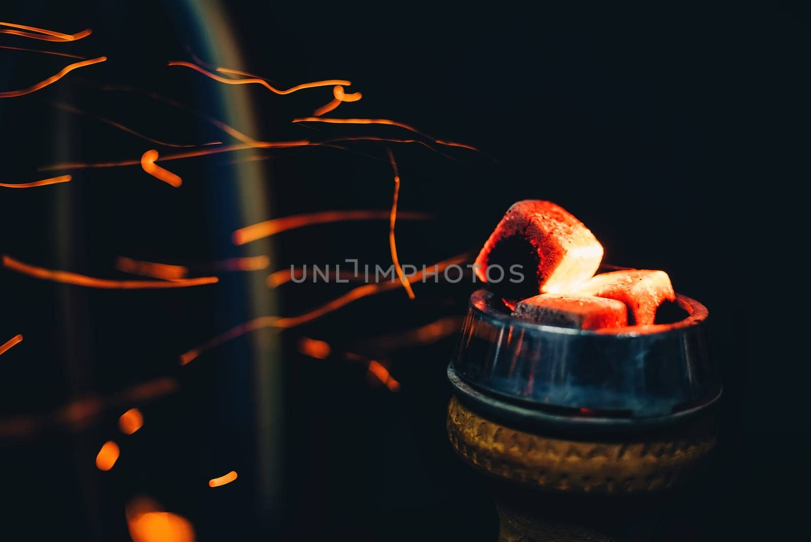 bowl of the hookah with hot coals heated Smoking area and rest with red sparkles on a dark background
