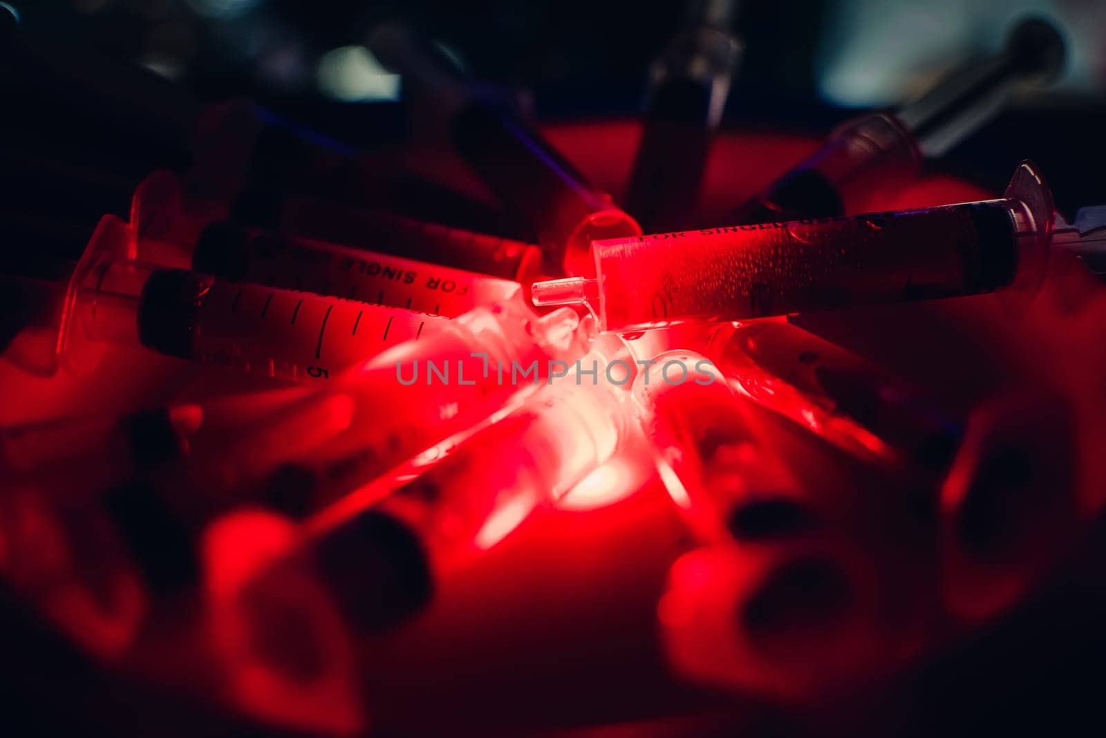 syringes with blood clearance Halloween horrible on a dark background with red lighting and alcohol