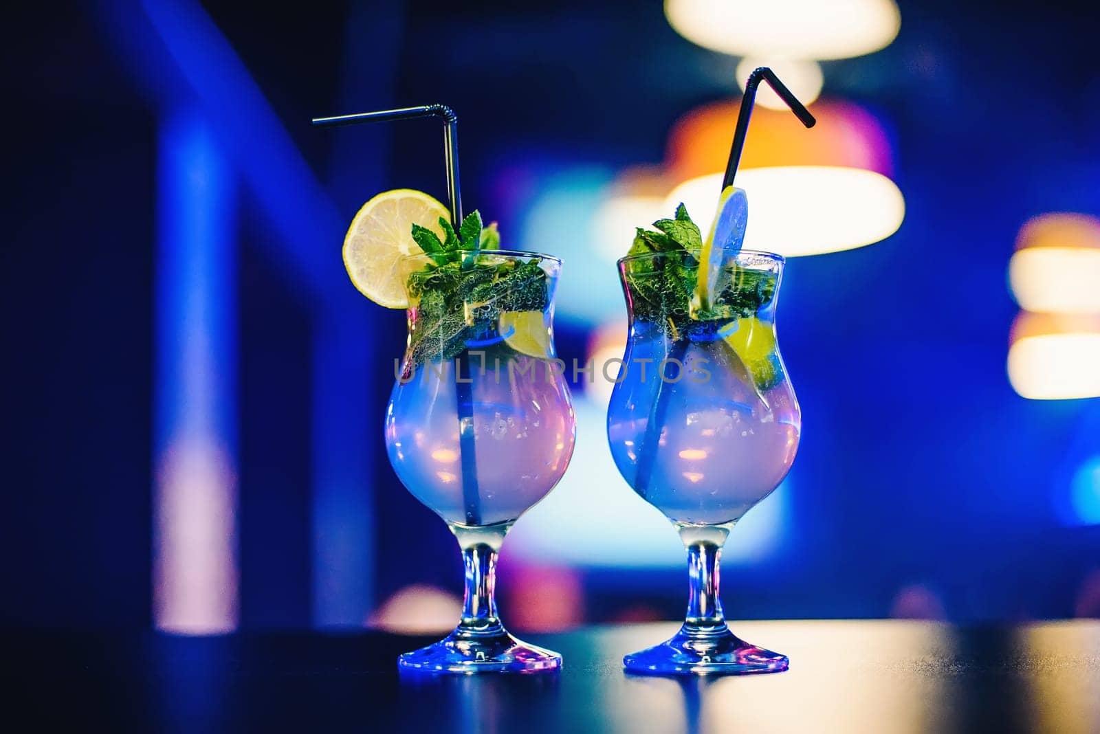 two glass of Mojito cocktail with straws lime and mint at the party on bright blurred background