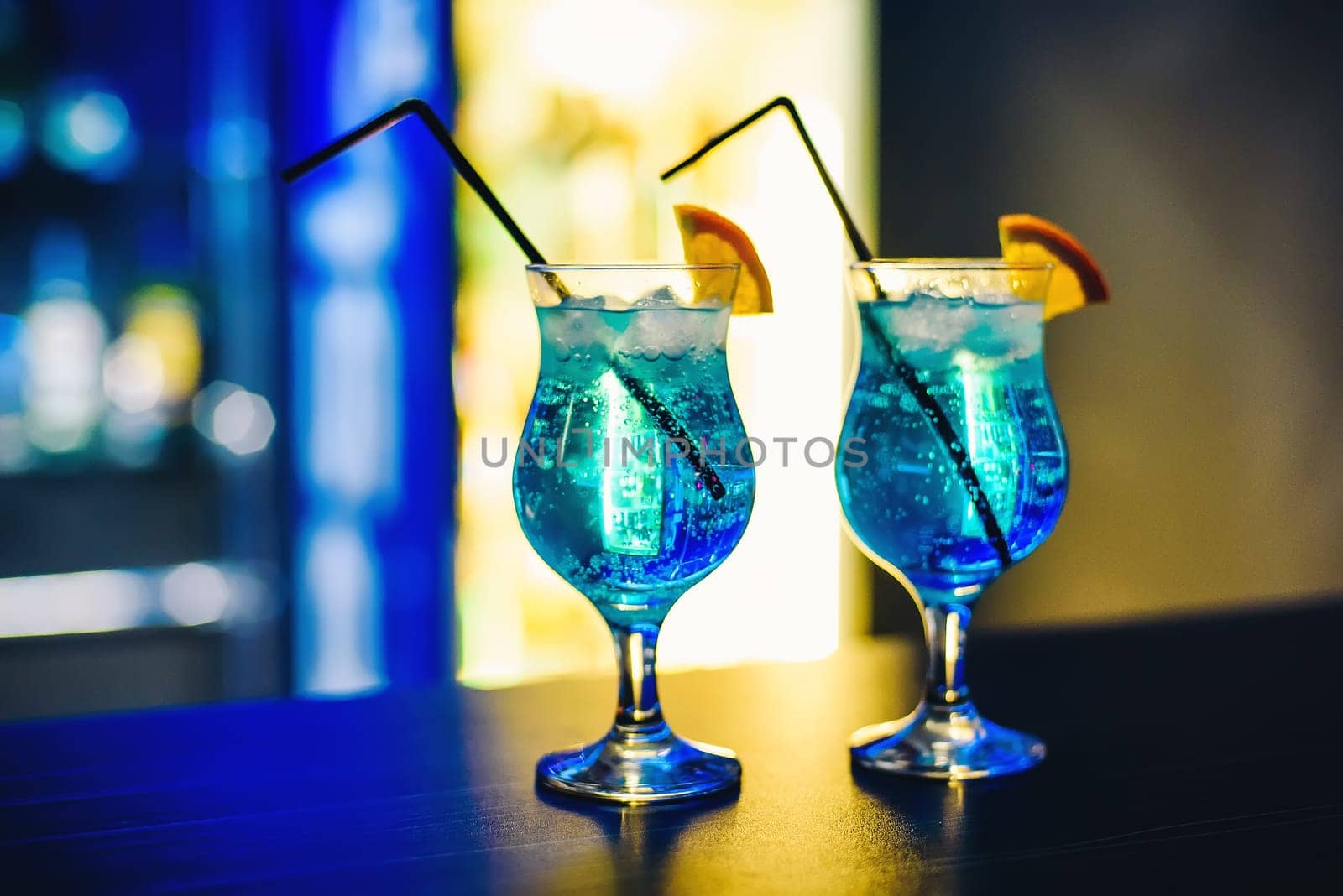 martinis in glasses with ice on the bar with orange and blurred background