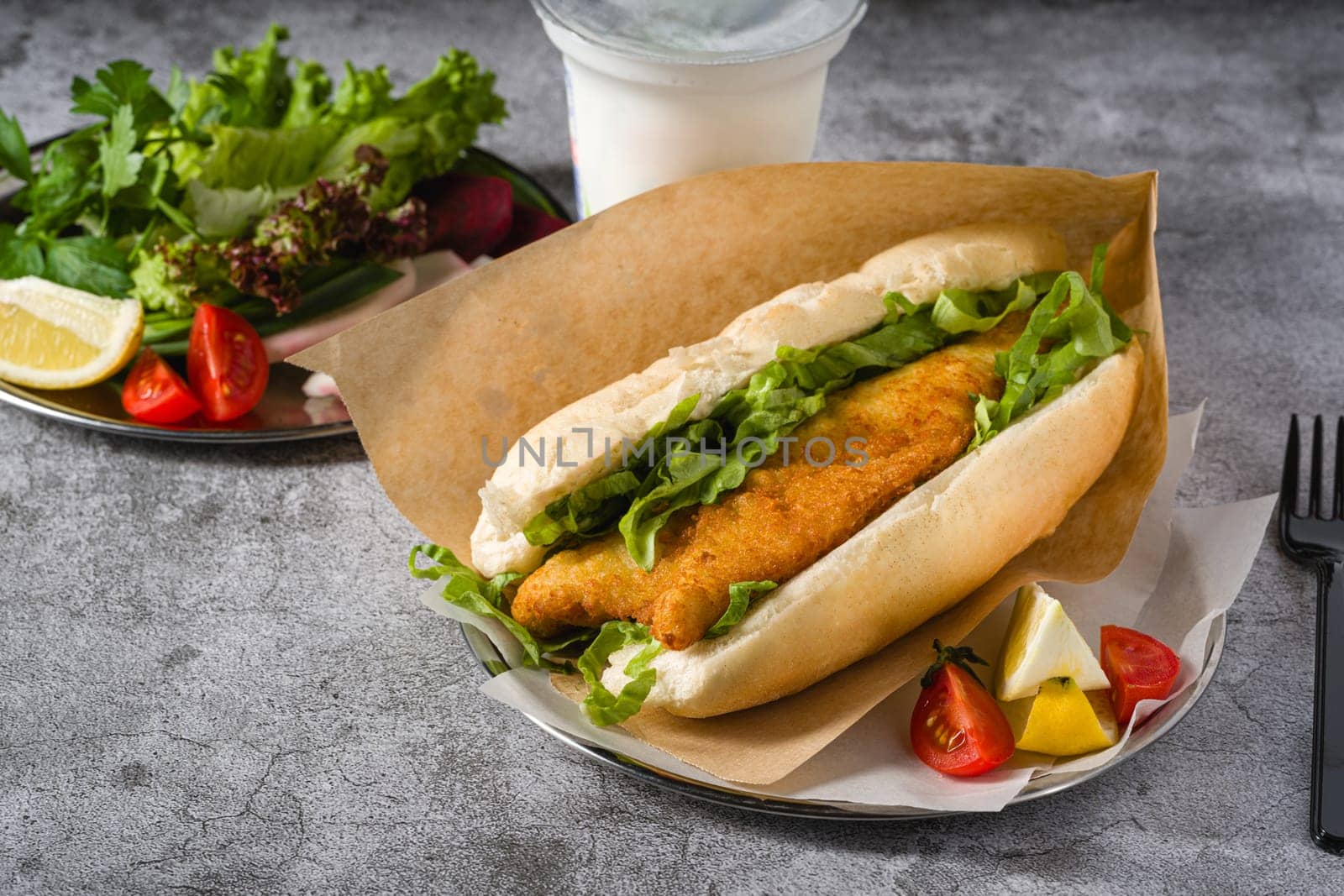 Fried fish sandwich with greens on the stone table. Turkish name Balik Ekmek by Sonat