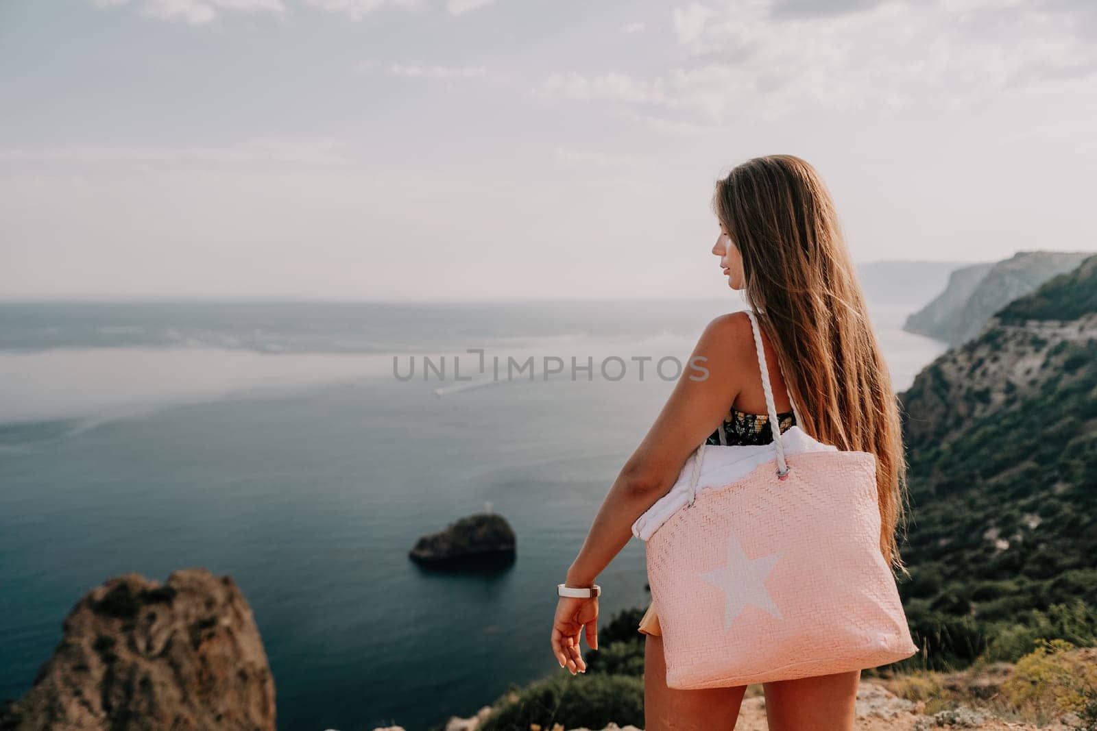 Woman travel sea. Happy tourist taking picture outdoors for memories. Woman traveler looks at the edge of the cliff on the sea bay of mountains, sharing travel adventure journey.