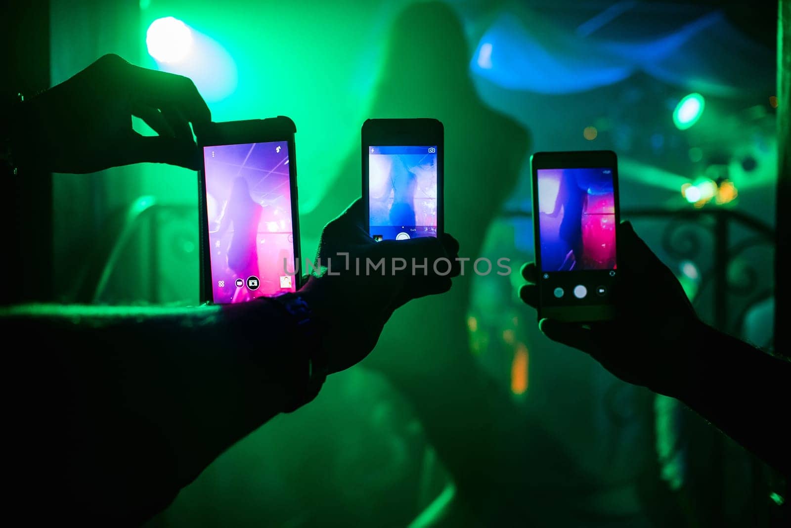 men's hands with smartphones take pictures of a dancer's ass in a nightclub
