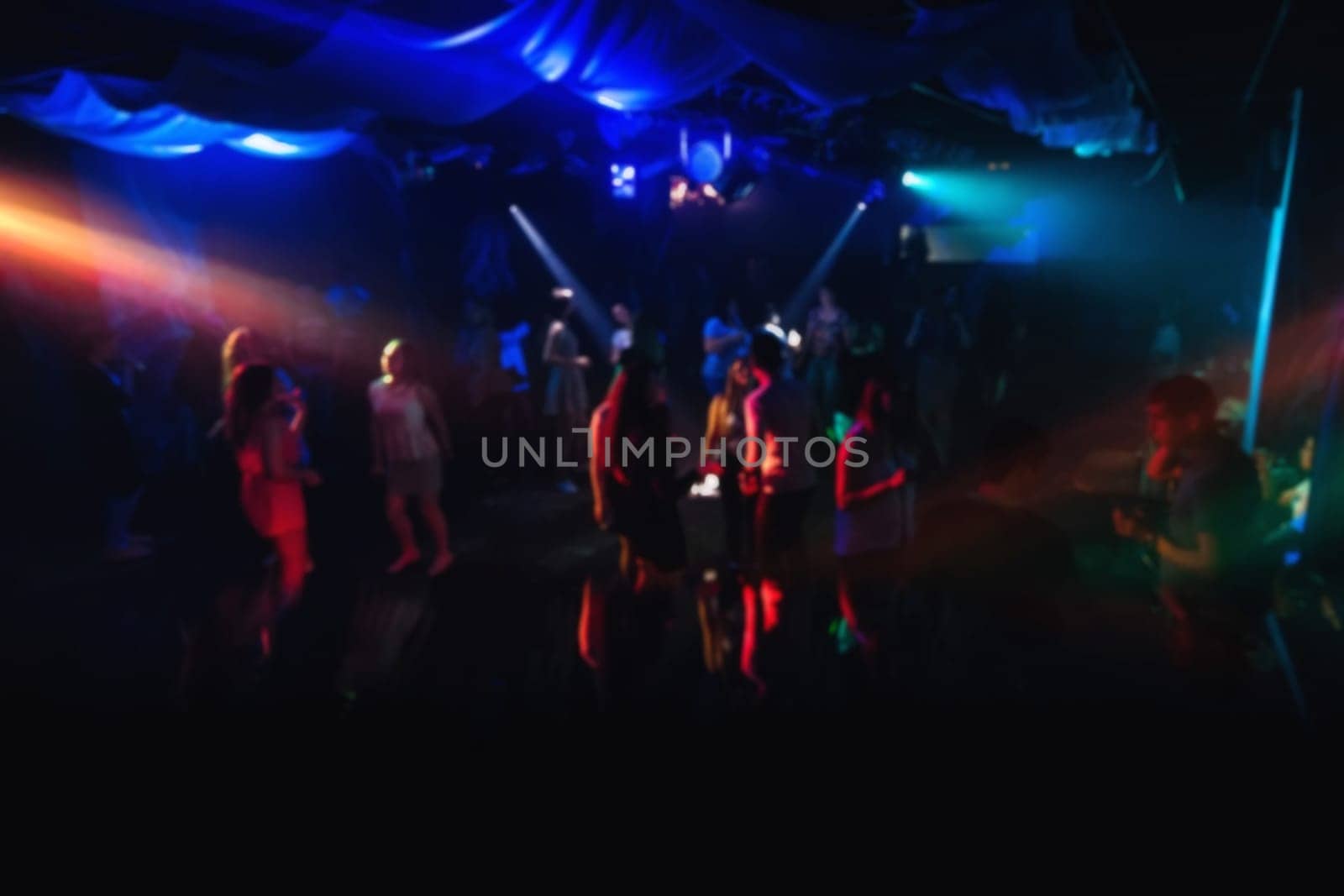 blurred people dancing on the dance floor in a nightclub on the dance floor with colorful background