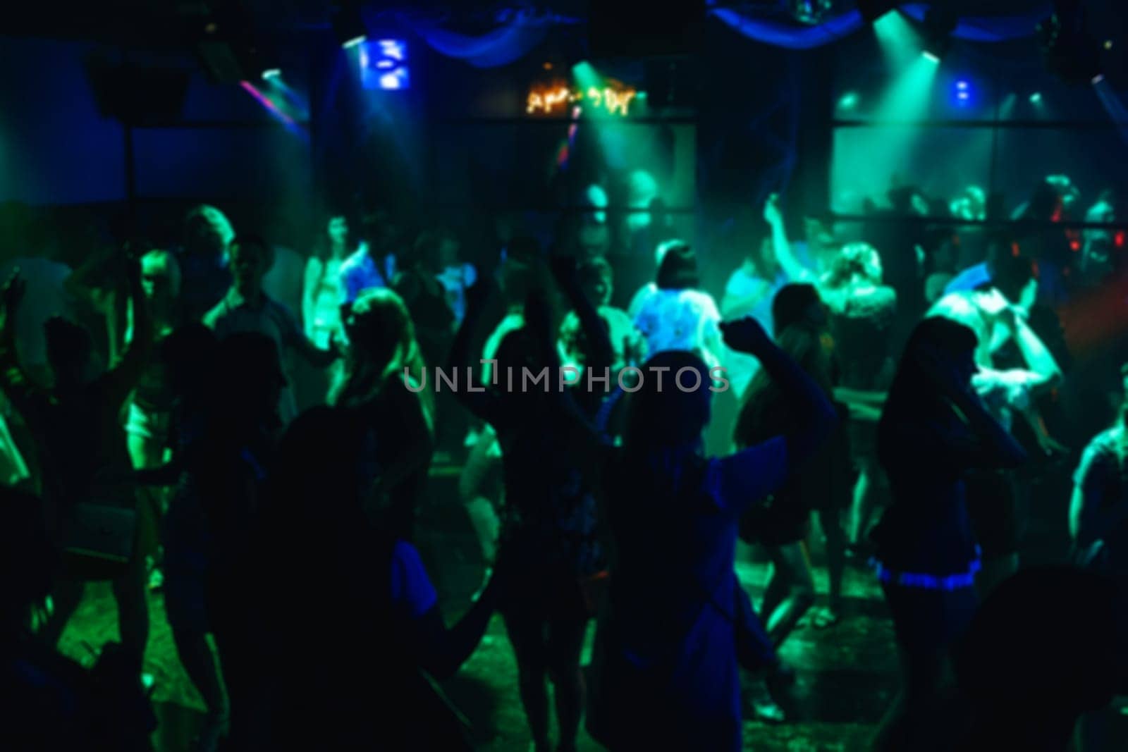 blurred silhouettes dancing merry men on the dance floor at the concert in a nightclub