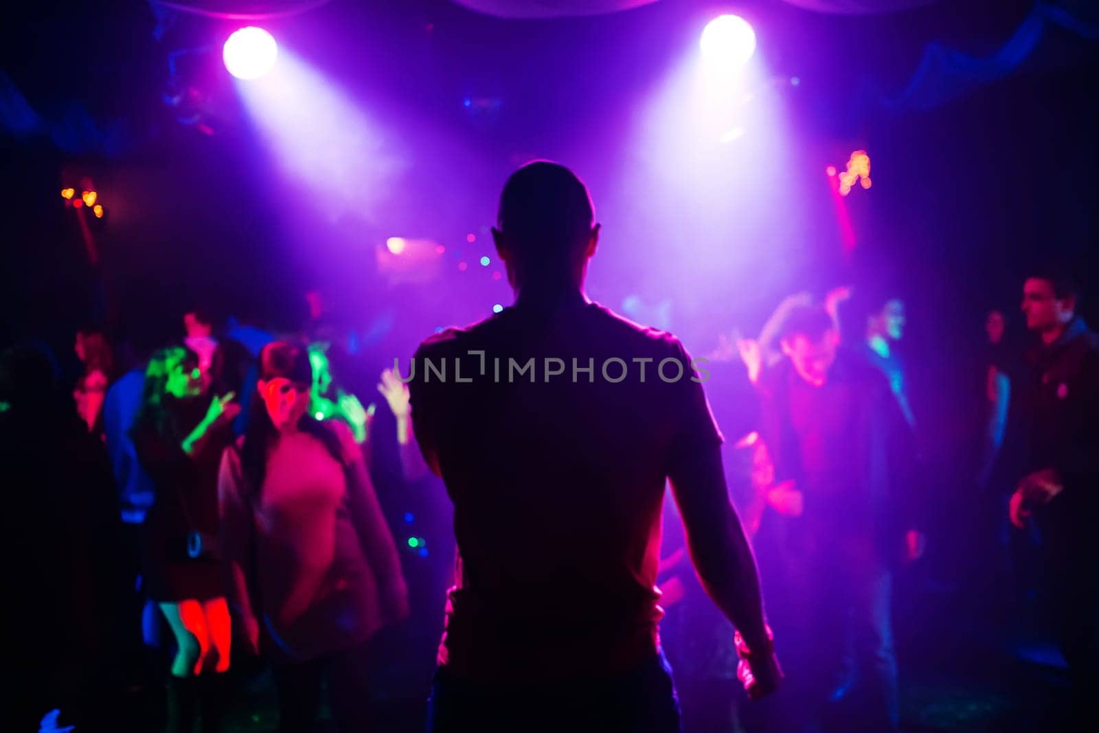 blurred silhouette of the MC with a microphone on stage of nightclub