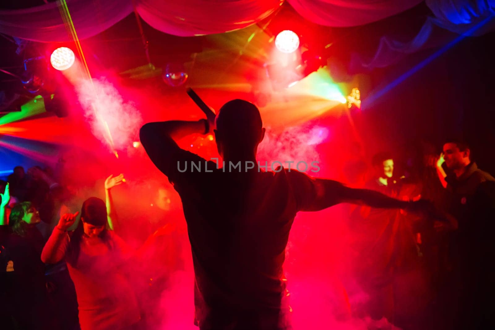 blurred silhouette of the MC with a microphone on stage of nightclub