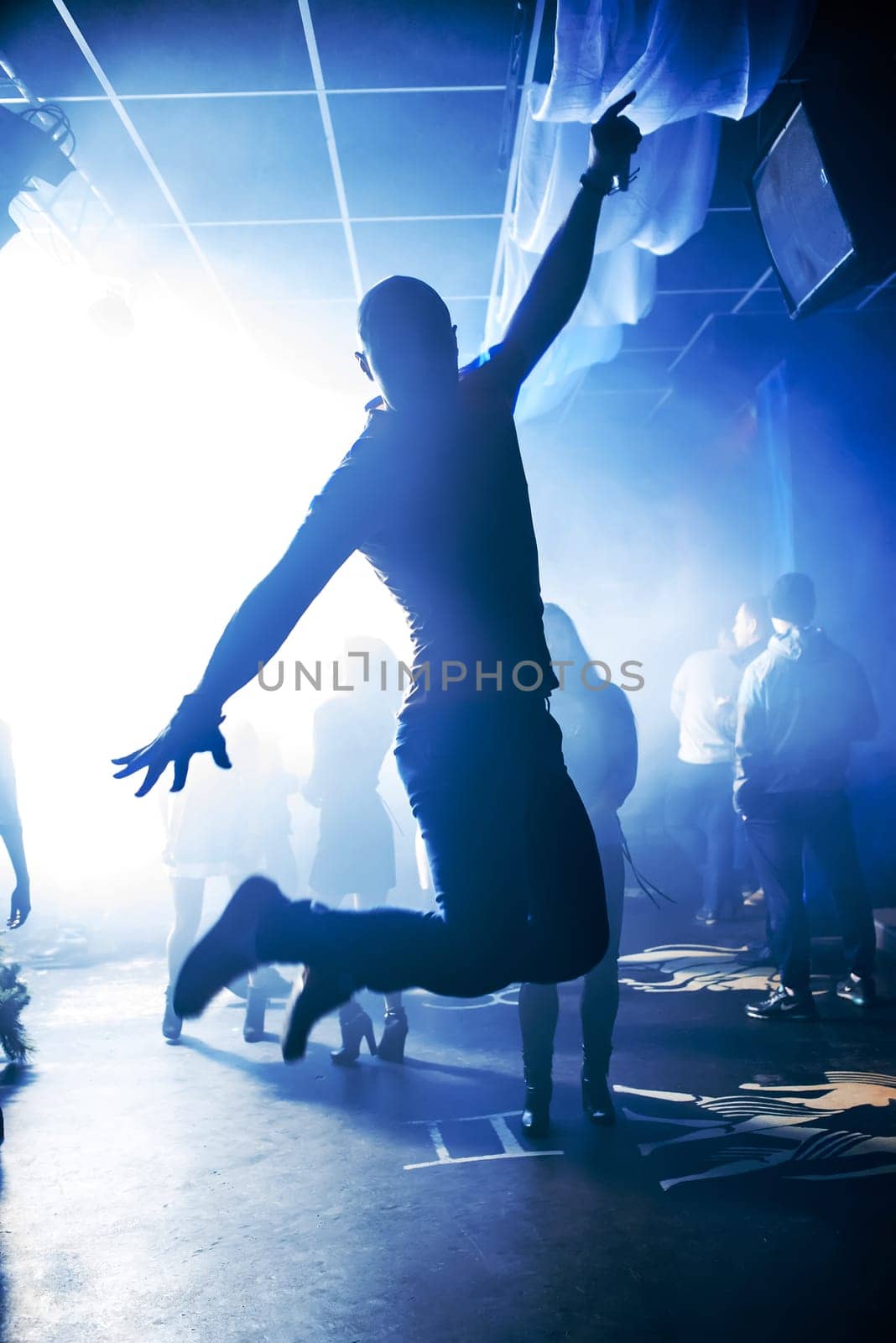 blurred silhouette of the MC with a microphone on stage of nightclub