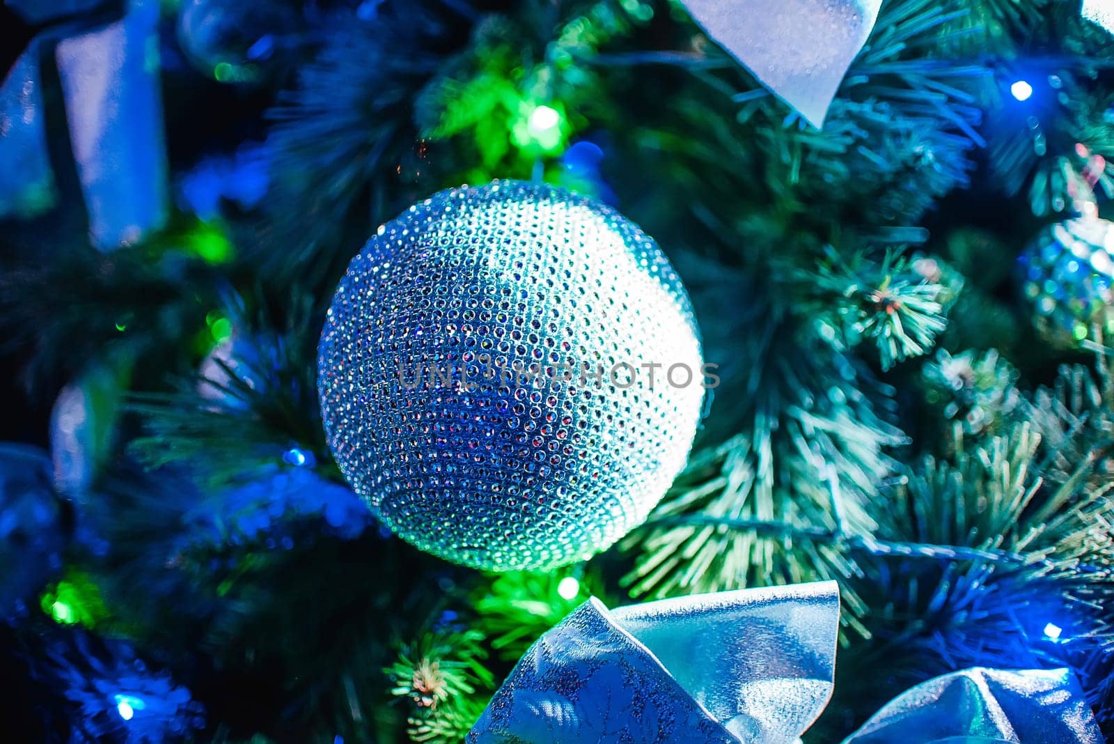 ball on the Christmas artificial trees branches on branches closeup with colorful lights and the blurred background
