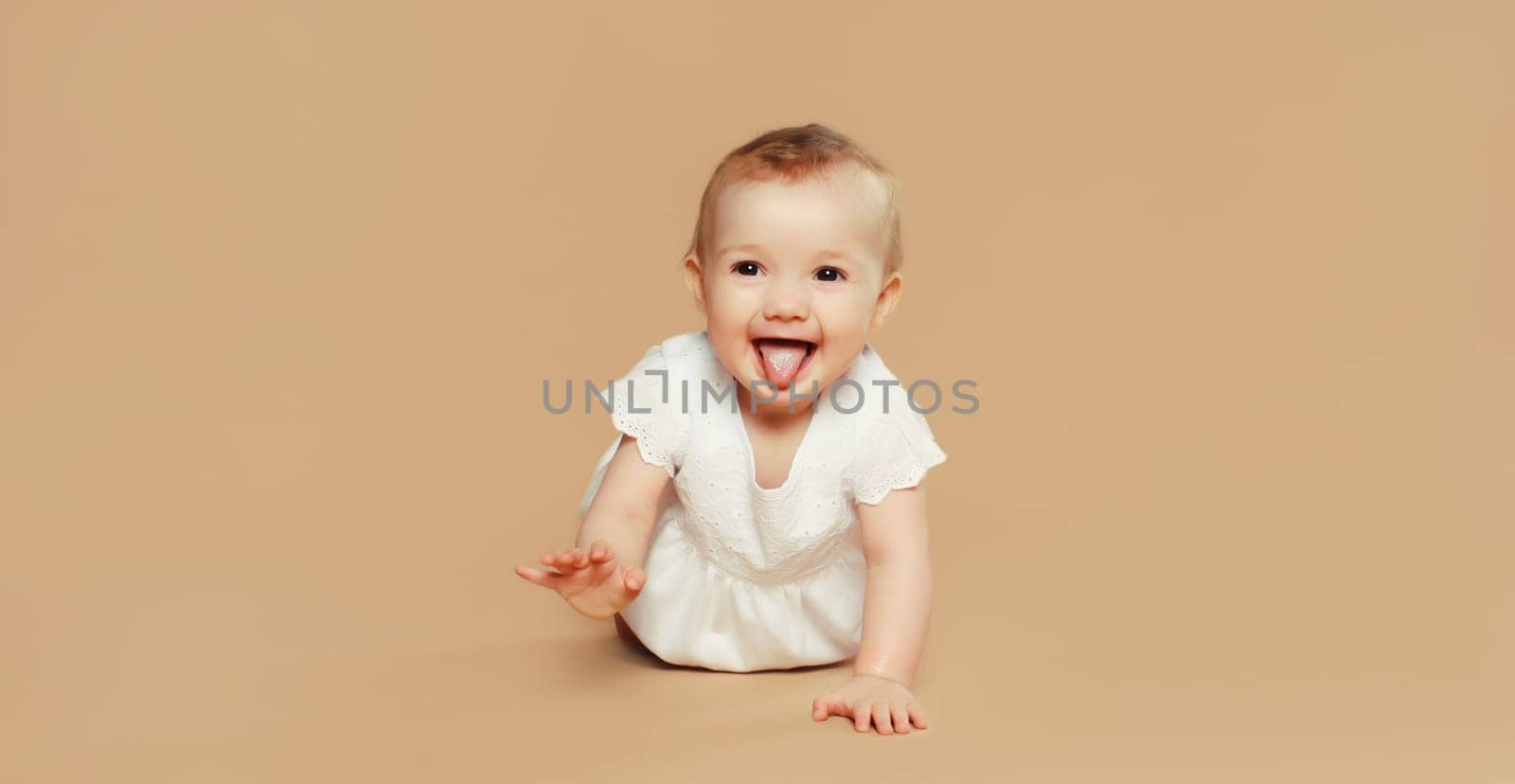Portrait of happy cute baby crawling on the floor on brown studio background