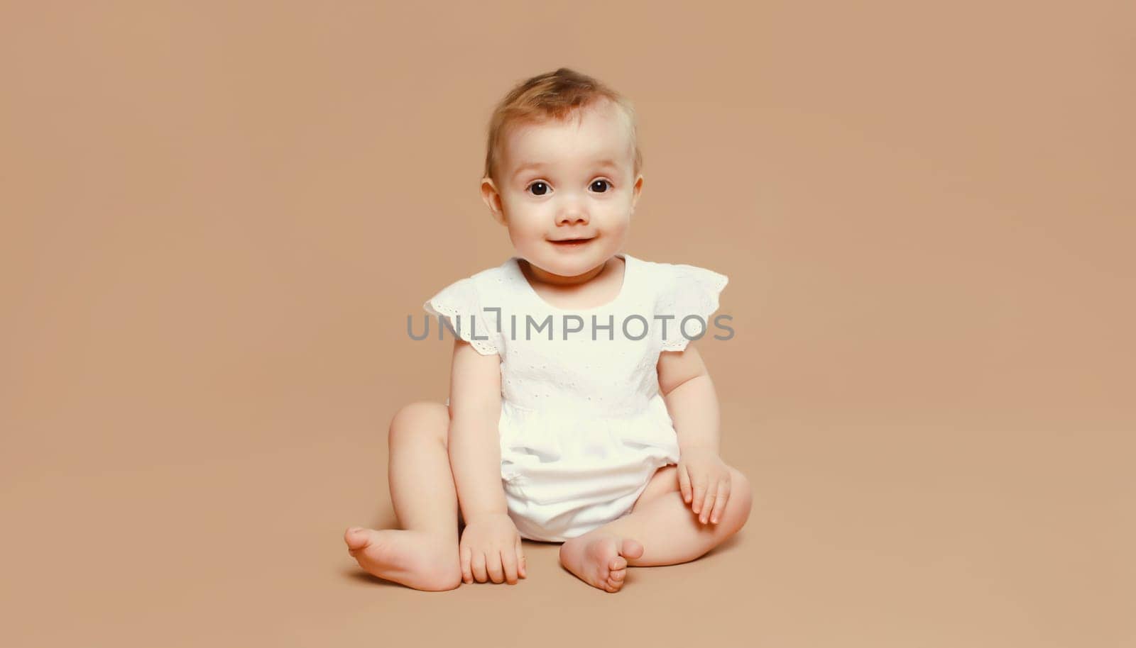 Happy cute baby crawling on the floor on brown studio background by Rohappy