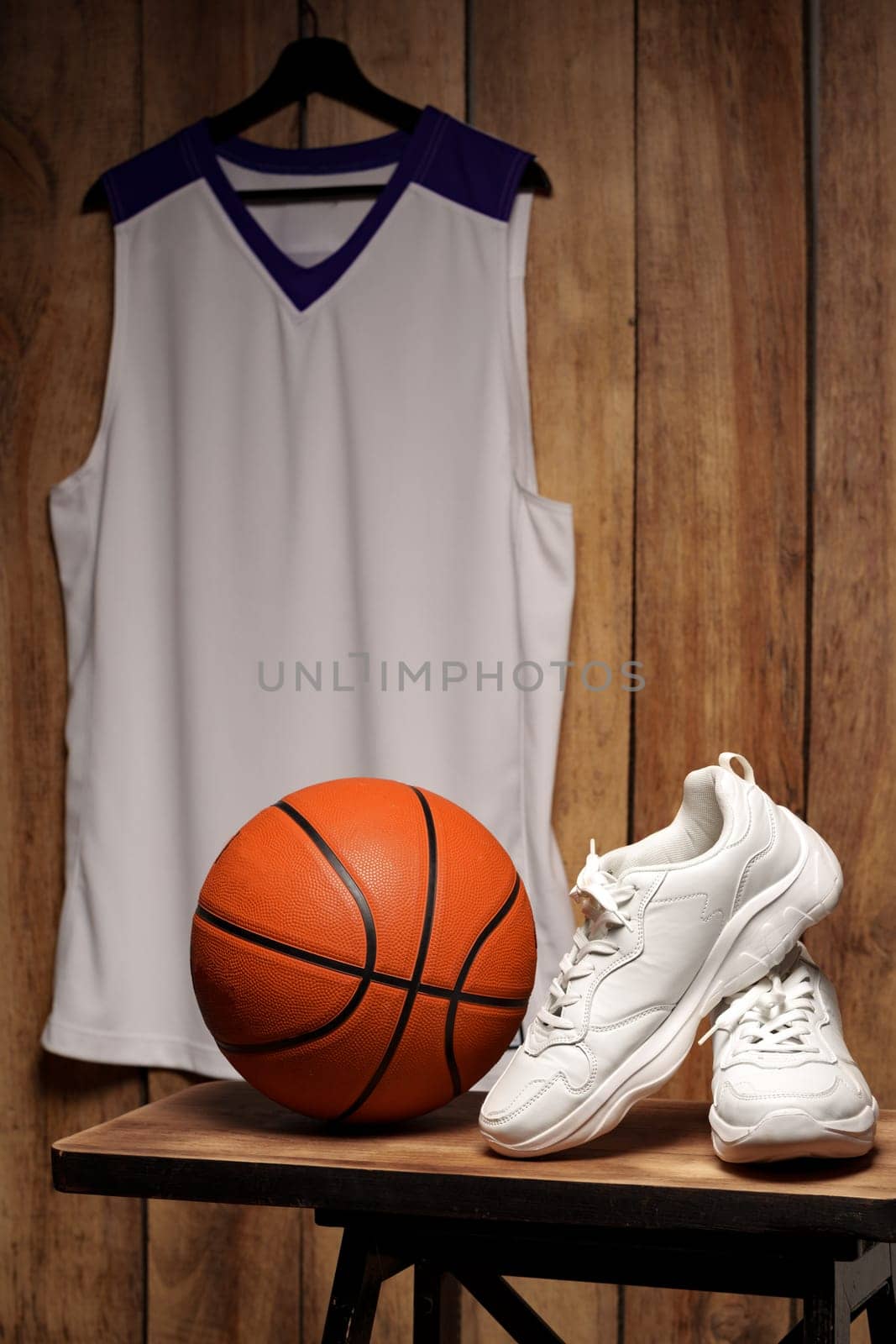 White sneakers and basketball ball against wooden background by Fabrikasimf