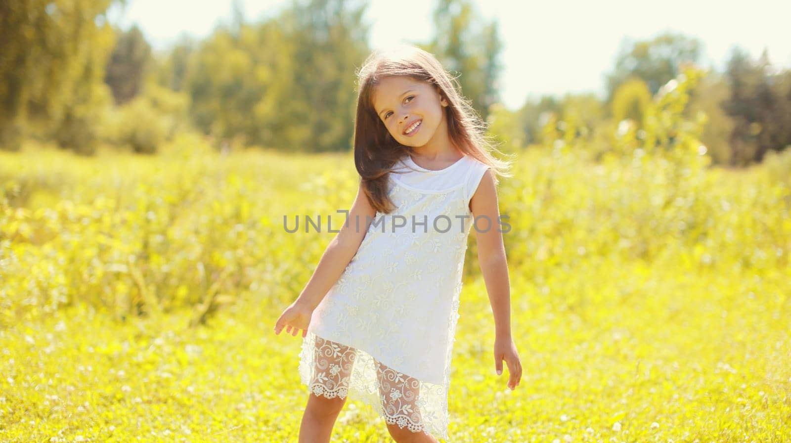 Portrait of happy little girl child walking in sunny summer park