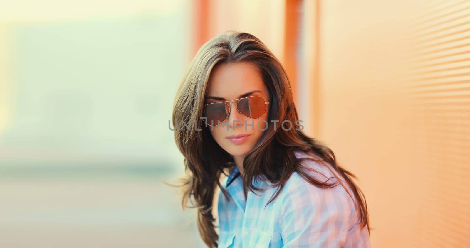 Portrait of beautiful brunette young woman in sunglasses posing in the city