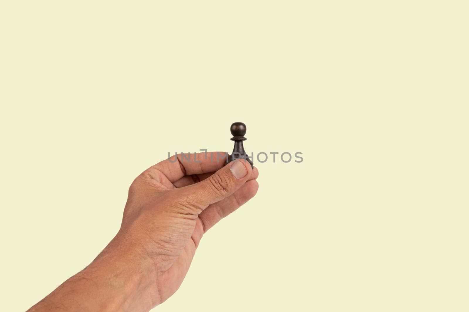 Isolated hand holding a chess figure light green background. High quality photo