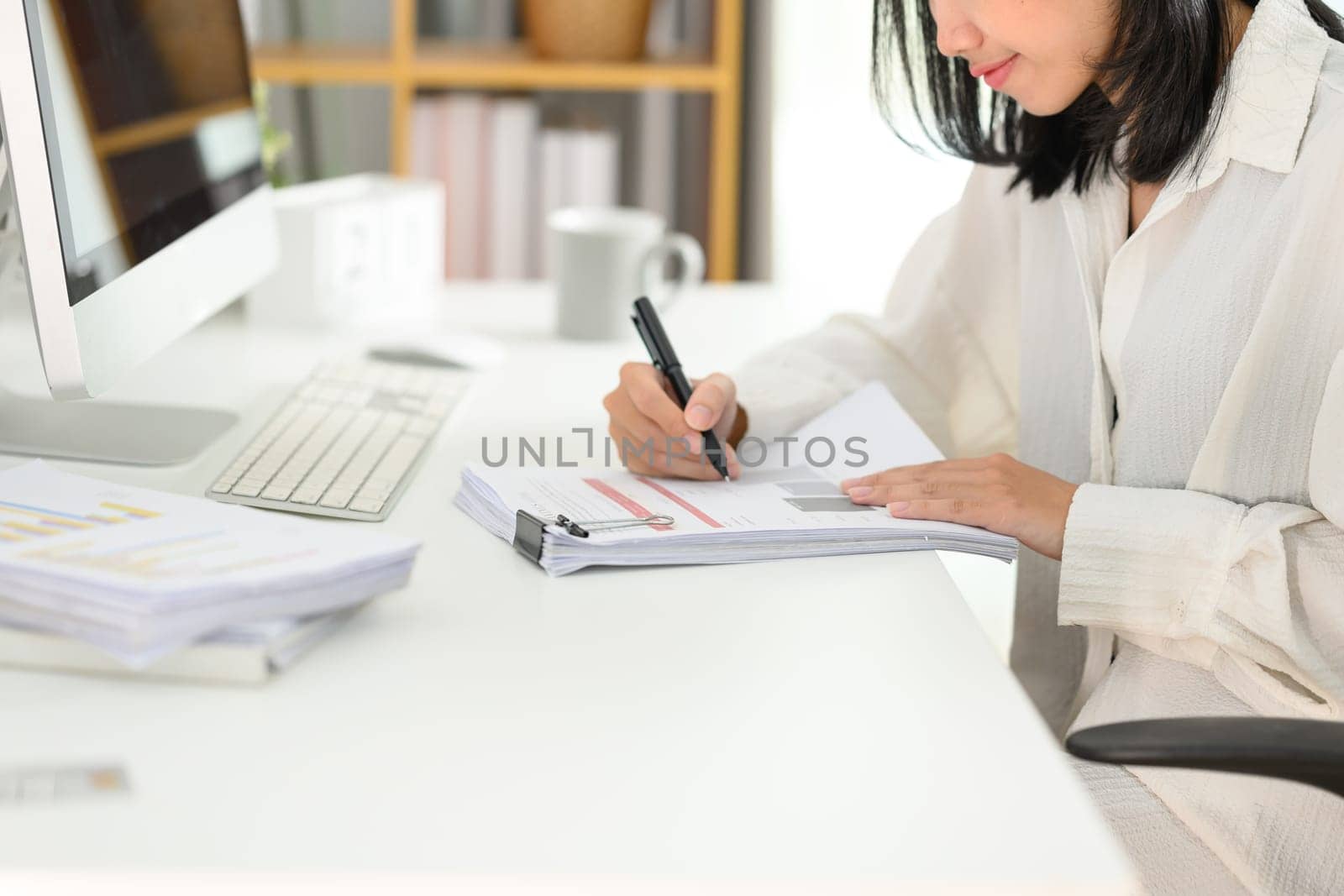 Side view of focused businesswoman analyzing marketing data at desk by prathanchorruangsak